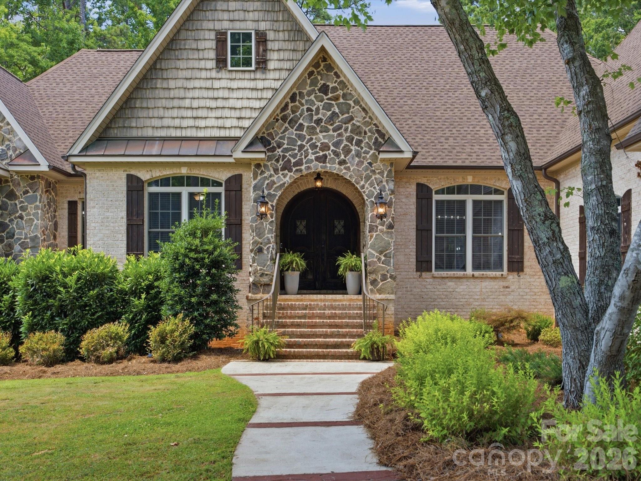 Gorgeous custom home sitting on nearly 2 acres of wooded property that offers an exceptional wooded retreat. Recent updates include a brand new roof installed in 2024, interior light fixtures and ceiling fans throughout, along with thoughtful updates to the basement. Enjoy the Carolina lifestyle from the massive screened-in porch featuring an outdoor fireplace overlooking the fenced backyard. The main level offers a huge master suite with access to the screened porch and an open floor plan with great room that includes a gas fireplace, centered around a beautiful kitchen with multiple French doors leading outside — perfect for entertaining. Main level has a large laundry room with folding area and cabinet. The finished basement has been thoughtfully updated with a full kitchen and additional washer and dryer hookups, along with comfortable living area that includes a gas fireplace and features LVP flooring and carpet in all three bedrooms. A standout feature is the impressive television wall with four large integrated screens that will stay with the home — ideal for sports lovers to watch games or for hosting guests during game days and gatherings. Additional features include a 3-car attached garage and a 2-car detached garage with a separate 1-bedroom apartment above — ideal for in-laws or guests. There’s also an unfinished walk-up attic that would make an excellent bonus room, plus flexible space that can be used however you need. Conveniently located just 2 miles from I-77, only 15 minutes to Rock Hill, and 40 minutes to Charlotte.