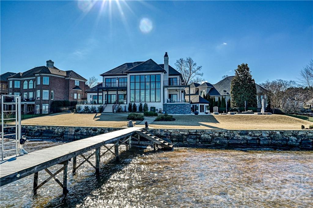 Perfectly positioned on a rare and most desirable lakefront point lot with meticulously manicured grounds, this iconic masterpiece includes 175 feet of pristine lake frontage and panoramic views on Lake Norman. Rebuilt to redefine elegance and one-of-a-kind luxury living and inspired by lakeside views and the relaxed lifestyle offered in the Peninsula. Designed with comfort in mind, refined rustic architectural details provide an organic contrast to the contemporary touches creating the perfect blend of coastal modern and serene relaxation. A wall of expansive windows perfectly captures the beauty of the lake, 4 en suite bedrooms, a chef's dream kitchen, and a wine cellar enrich the luxe hosting and comfortable living. The ultimate in outdoor experience awaits with a cabana, salt water pool, and private boat dock for endless fun. From vivid sunsets to colorful sailing regattas and a dreamy setting for relaxing and entertaining, this home is meant to be enjoyed for generations to come
