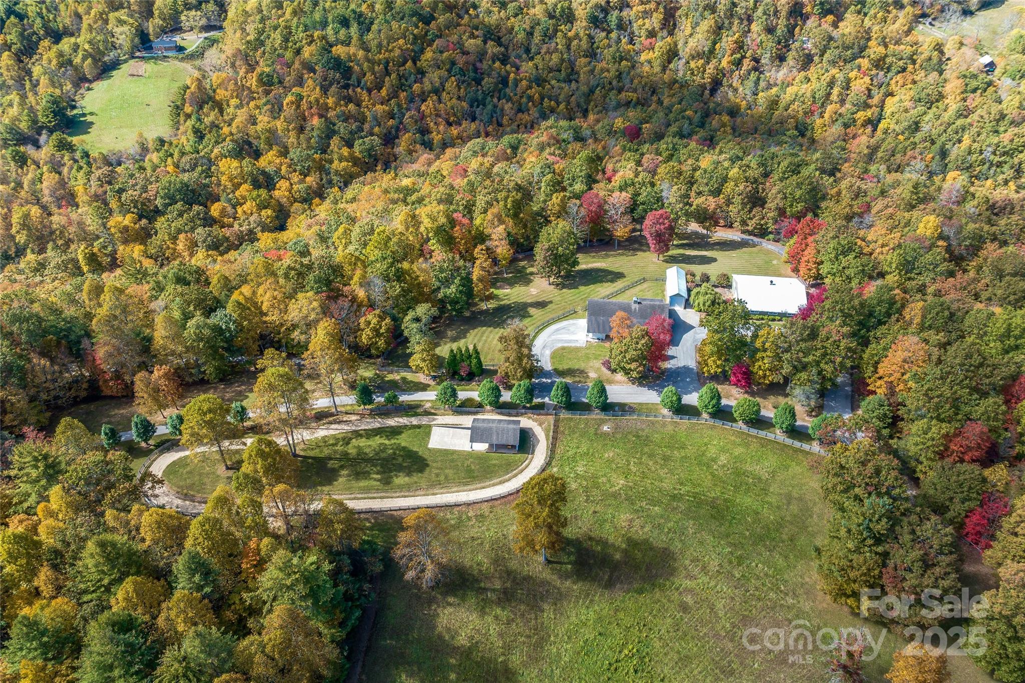A tree-lined drive welcomes you to this premier gated 68-acre equestrian estate with sweeping mountain and pastoral views. The Estate offers a stunning main house and pristine equestrian facilities. The heated stable is a center aisle design with 6 stalls, wash stall, tack room, hay barn and studio apartment. Adjacent to the stables is an indoor riding arena, outdoor riding track, RV/horse trailer garage, and pavilion with views. The main residence showcases soaring tongue-and-groove ceilings, a floor-to-ceiling stone fireplace, chef’s kitchen, and expansive mountain views. The estate also features shoreline along Crabtree Creek with a multi-tiered waterfall and fenced pastures. Located just one hour from Asheville, 15 minutes to Spruce Pine and Burnsville, and 10 minutes to the Blue Ridge Parkway. The Tryon International Equestrian Center is just under ninety minutes away. A rare offering of luxury, endless mountain views, and world-class equestrian facilities in the heart of WNC.