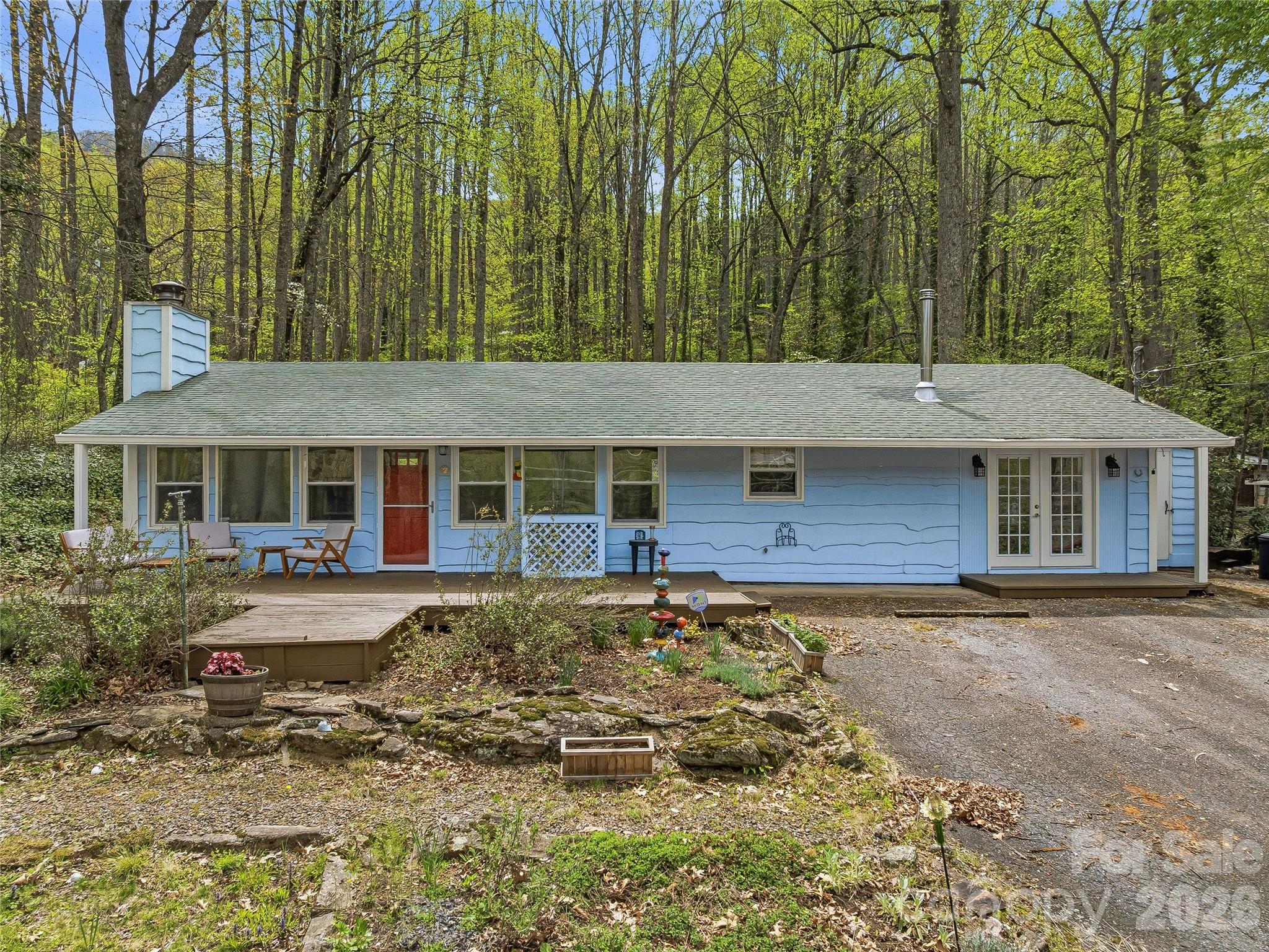 Enjoy easy one-level living in this inviting Maggie Valley home, where comfort and functionality come together in a peaceful setting.  A charming front porch welcomes you, overlooking a beautiful front yard with mature landscaping and garden beds. Inside, the home offers a flexible layout with a spacious bonus room that can easily adapt to your needs—whether as a den, office, or additional living space.  The living room features a cozy wood-burning stone fireplace, while a wood stove in the bonus room adds warmth and character. Both bedrooms offer privacy and convenience with en suite bathrooms—one featuring a walk-in shower and the other a tub/shower combination.  Step out back to a large, fenced backyard—perfect for pets, gardening, or entertaining—with a storage shed for added convenience. A separate workshop/storage space with electricity provides excellent room for hobbies or projects (not included in square footage and not heated). This property offers a wonderful blend of charm, versatility, and practical living in Maggie Valley.