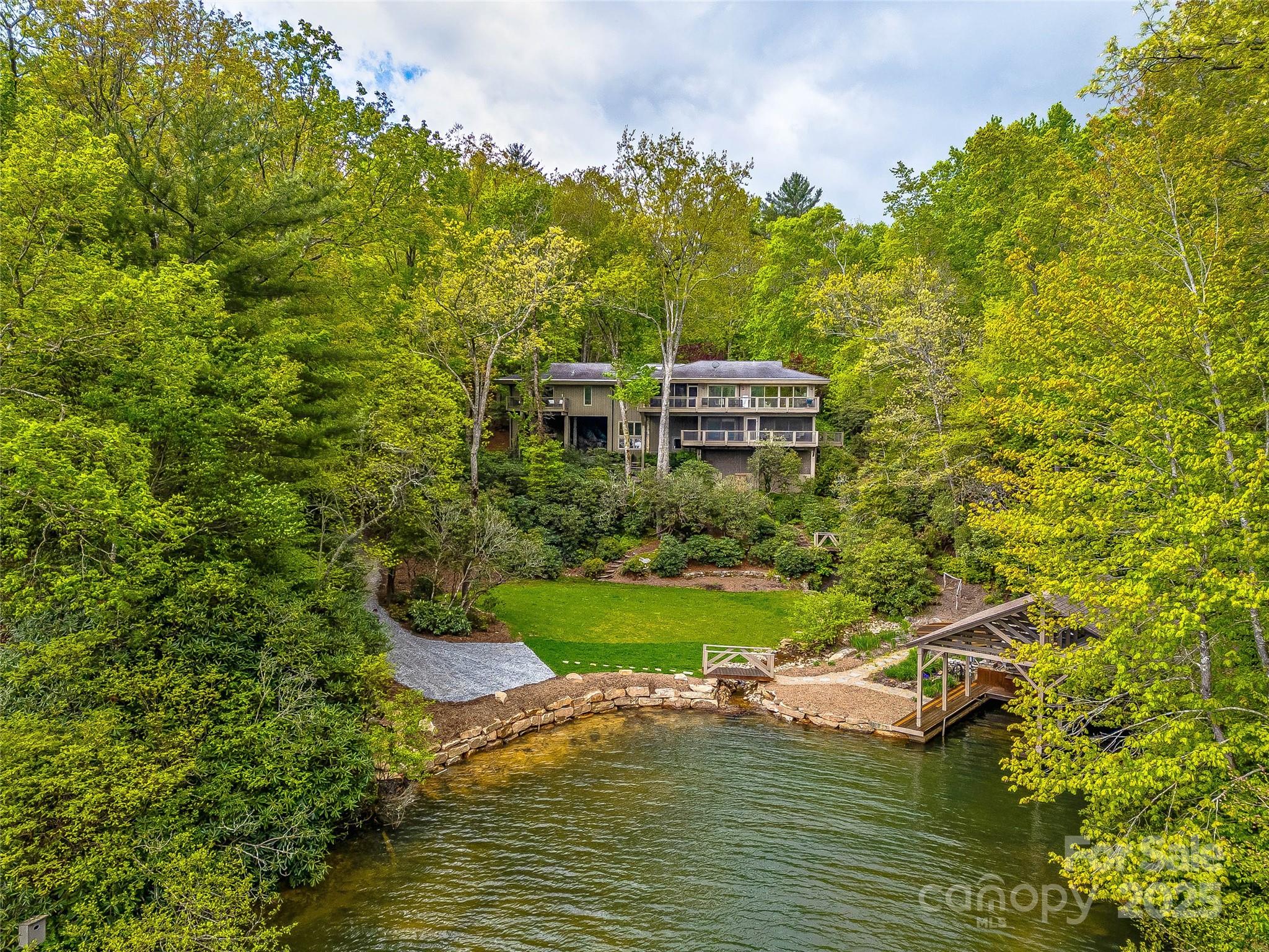 This architectural private retreat offers stunning lake views & unbeatable outdoor living. A lush lawn and patio create the perfect waterfront setting, while a brand-new seawall and dock provide safe and easy lake access. The two-bay boathouse is conveniently nestled in a private cove. A natural water feature flows from the top of the property down to the lake. Expansive decks capture breathtaking lake views, seamlessly connecting to the home’s main living spaces. With over 4,600 sq. ft. on an oversized and additional lot totaling ~3.4 acres, this private retreat features two primary suites on the main level. Entertain effortlessly with a built-in wet bar, expansive deck views from the living, dining, and kitchen, and a spacious sunken family room. The interior walls are butternut paneling, a soft lightweight hardwood that’s prized for its clean lines and classic appearance. This is lakeside living at its finest close to LTCC. Space to entertain, relax, & enjoy the beauty of the water.