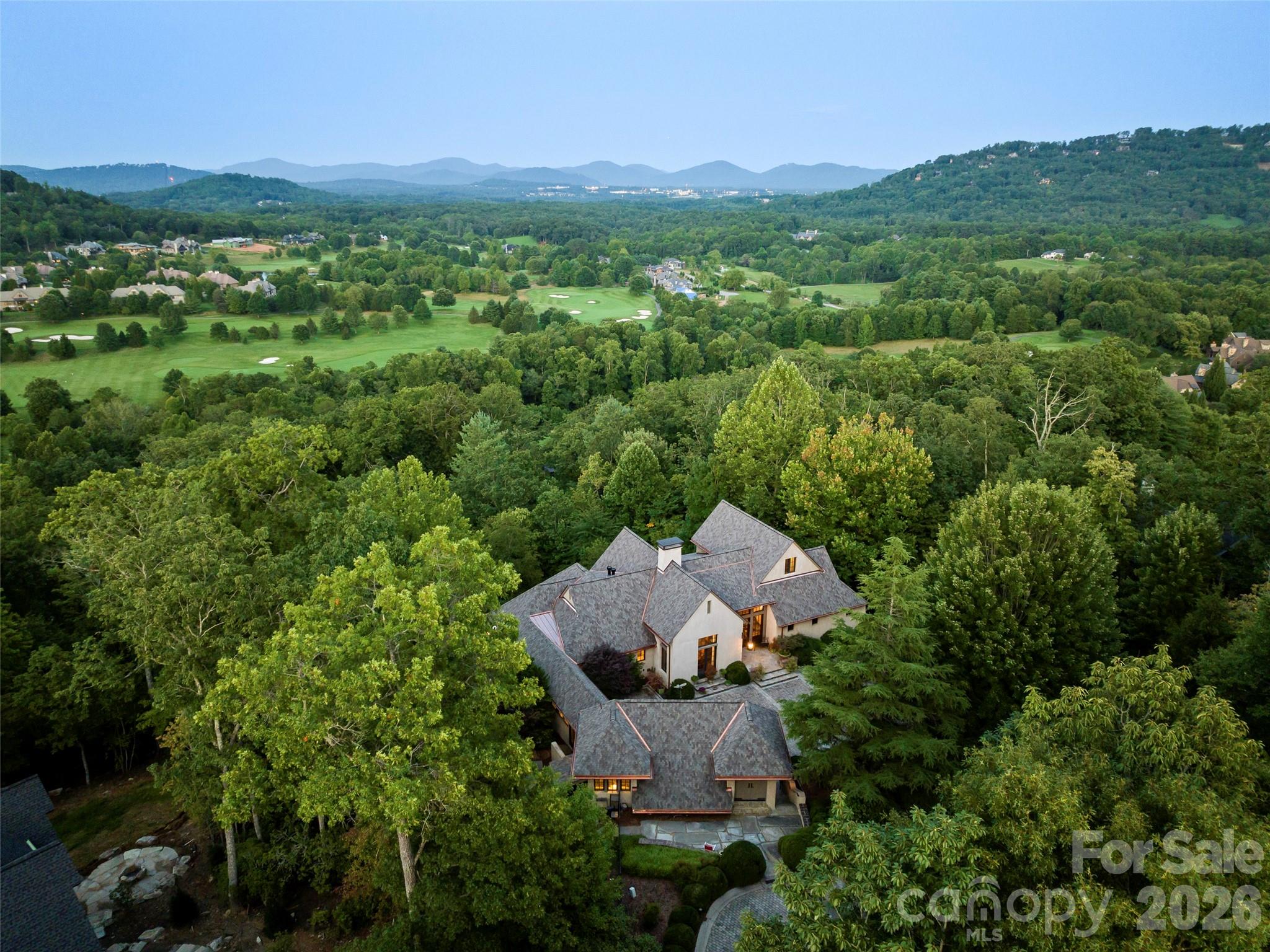 This luxury mountain enclave in Arden’s premier gated community combines sophisticated French Country charm with the world-class amenities of The Cliffs at Walnut Cove. A gentle driveway and expansive brick-paver private courtyard provide a grand welcome to the home, where long-range mountain vistas are visible from nearly every room. The heart of the residence is a professional French Country kitchen featuring oak and copper accents, a separate pantry, and a sunlit breakfast room with a retractable wall that opens directly to the outdoor dining porch. On the main level, the primary suite serves as a true sanctuary with beamed ceilings, a private screened porch, and a spa-inspired bath complete with radiant heat floors, a steam shower, and a whirlpool tub.  The home’s architecture is defined by soaring two-story beamed ceilings and clerestory windows that flood the space with natural light. A home elevator offers easy access to the terrace level, where hidden bookcase doorways lead to private guest quarters and a gorgeous oak wet bar. Outdoor living is equally impressive, featuring a fenced level yard, four private screened porches, and an expansive flagstone terrace framed by a stone retaining wall and a built-in gas firepit—perfect for enjoying the cool mountain air.  Living in The Cliffs at Walnut Cove provides a lifestyle of unparalleled luxury. Residents enjoy access to a Jack Nicklaus Signature golf course, a state-of-the-art wellness center with indoor and outdoor pools, and miles of hiking trails that connect directly to the Blue Ridge Parkway. The community's social life centers around the elegant clubhouse and the Golf House Tavern, offering both fine and casual dining options just minutes from your front door.