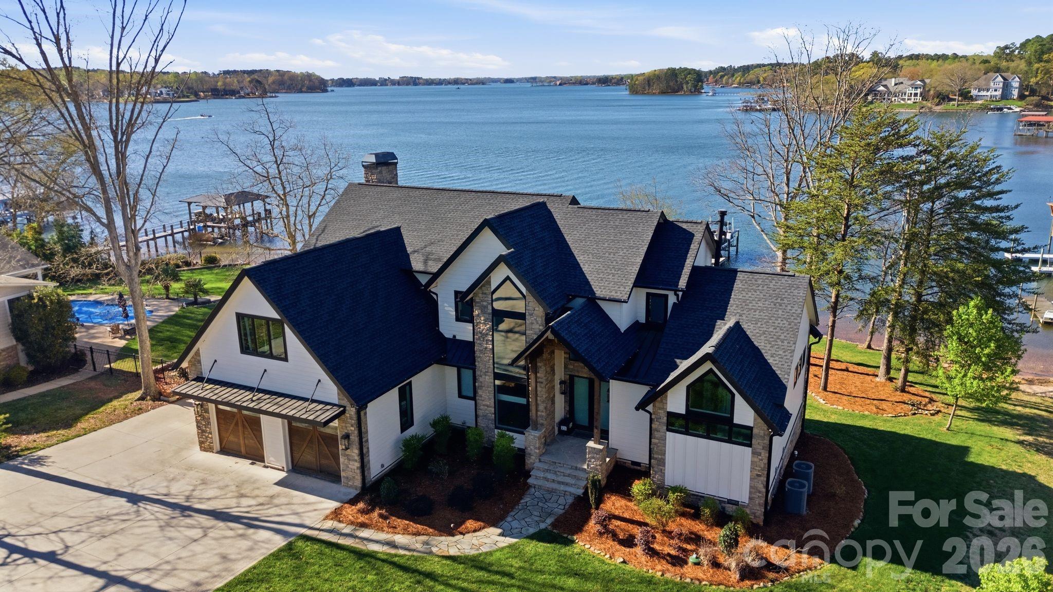 Architecturally designed to capture the beauty of its exceptional waterfront setting, this custom-built Lake Norman residence offers a rare combination of expansive main channel views and protected waters, delivering both breathtaking scenery and a more enjoyable lakefront experience. Custom crafted by a highly regarded local builder and not occupied until June of 2021, this home showcases superior craftsmanship and thoughtful design throughout. The open-concept main living area is anchored by a chef’s kitchen featuring Thermador appliances, custom cabinetry, and an oversized island, flowing into a vaulted family room accented by rustic beams and abundant natural light. Just beyond, a well-appointed scullery—complete with additional cabinetry, a second refrigerator, and a dedicated coffee bar—enhances both function and ease of entertaining. Designed for effortless indoor-outdoor living, the screened porch serves as a true extension of the home, anchored by an outdoor fireplace and thoughtfully designed for both relaxation and entertaining. A custom bar with pass-through windows opens to sit-in bar seating on both the interior and exterior—an exceptionally rare architectural detail that creates a seamless connection between the kitchen and outdoor living spaces. This feature enhances everyday living and entertaining, all set against serene, long-range water views. The main-level primary suite is positioned to take full advantage of the water views and features a tongue-and-groove vaulted ceiling that adds warmth and architectural detail. The adjoining bath mirrors this ceiling design and is anchored by an oversized tile shower, creating a clean, well-executed spa-like space.
Upstairs, three generously sized bedrooms, each with access to beautifully appointed bathrooms, provide excellent accommodations for family and guests. A spacious bonus room offers flexibility for a media room, playroom, or additional living space, while a separate upper-level laundry adds convenience. Outside, the property continues to impress with a private dock featuring multiple seating areas and a hard to come by boat ramp, positioned to take advantage of long-range views while avoiding the heavy wake typically associated with main channel locations. Whether enjoying quiet mornings on the water, fishing from the dock, or heading out for a day on the lake, this setting is truly exceptional. A rare offering that blends refined design, modern luxury, and one of Lake Norman’s most desirable waterfront experiences. 
7748 Harbor Lane — Where every room captures the water, and every detail captures the moment.