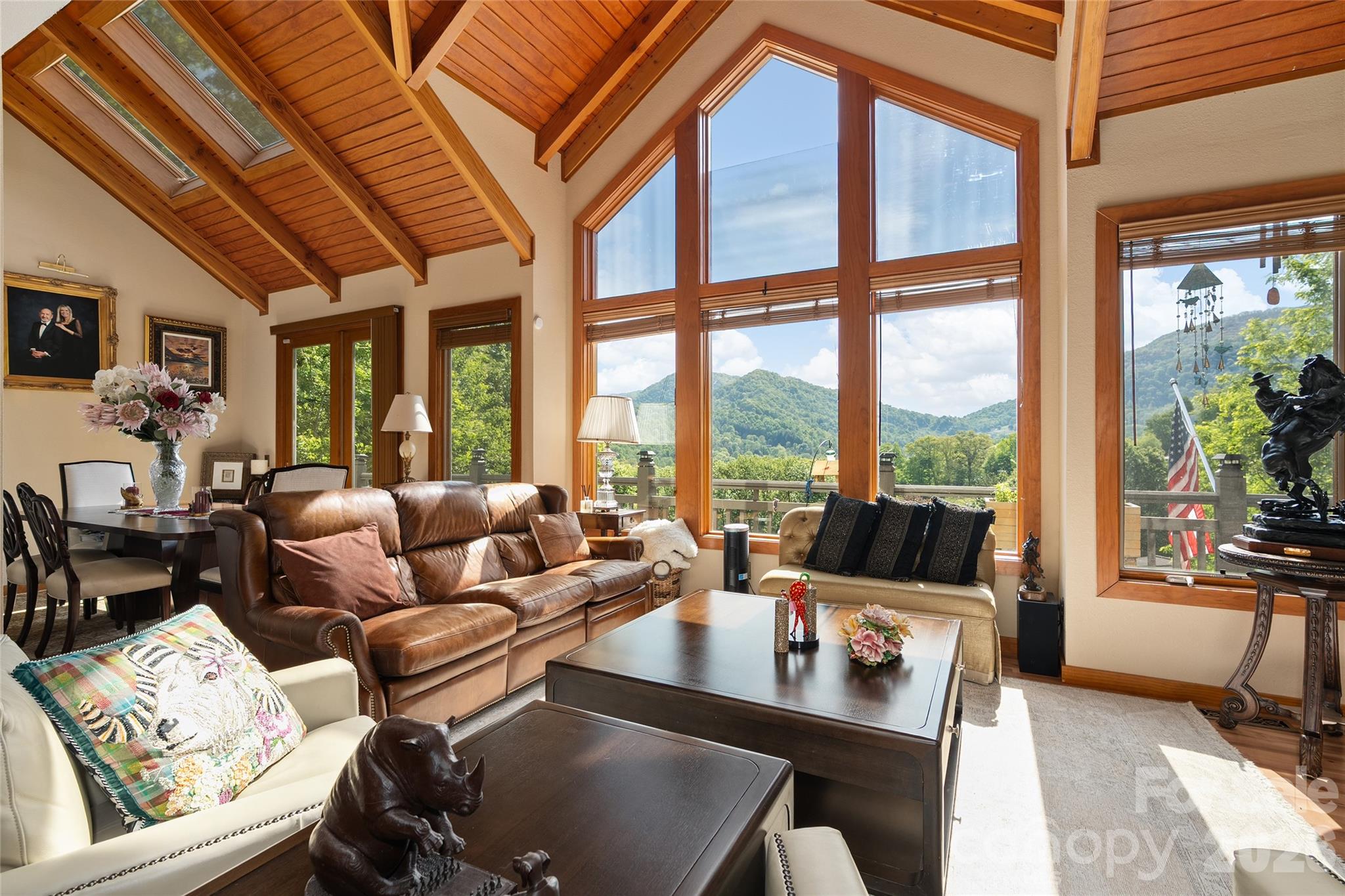 Perched on 1.54 acres across two parcels, this refined mountain residence offers a rare blend of privacy, convenience and sweeping long-range mountain views just minutes from Waynesville. Inside, vaulted tongue-and-groove ceilings with exposed timbers and expansive windows bring the outdoors in, filling the home with natural light and uninterrupted mountain scenery. The great room centers around a warm gas fireplace, creating an inviting focal point for gatherings. Two spacious en-suite bedrooms with walk-in closets and vaulted ceilings, plus a third en-suite bedroom, offer comfort with a generous sense of scale. Outdoor living is equally compelling, with wraparound decks designed for relaxation and entertaining, complete with a firepit and pergola. Multiple fenced areas with Astroturf provide practicality for pets. A handcrafted waterfall enhances the property with calming sounds of flowing water, elevating the overall mountain experience. Blending privacy, character and proximity to town, this is a mountain retreat built for everyday living and memorable escapes. Not in HOA and no HOA fee.
