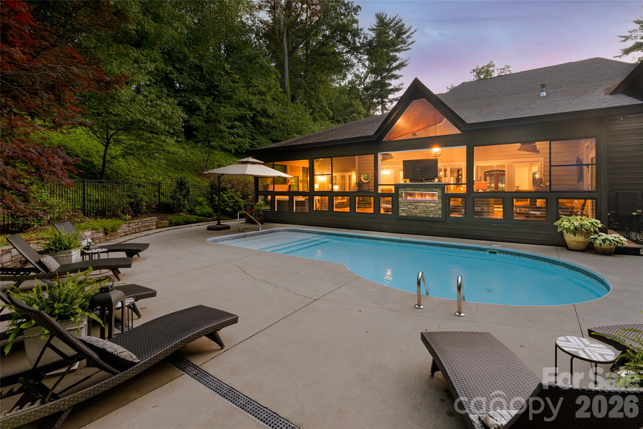 Set behind private gates on 3.78 acres, this distinguished Hendersonville estate offers a rare convergence of seclusion and everyday convenience, with Hendersonville Country Club, the Ecusta Trail, and the charm of downtown Hendersonville just a short distance from your doorstep. Thoughtfully designed for main-level living, the home opens to an exceptional outdoor environment where a heated pool becomes the focal point for gathering, complemented by a screened porch with a see-through fireplace, a private hot tub, and multiple spaces to relax, dine and entertain, all set against a serene wooded backdrop that provides privacy and a sense of retreat rarely found this close to town. Inside, the main level strikes a balance between openness and intention, anchored by a light-filled great room with a commanding stone fireplace and seamless connection to the outdoors. The kitchen is designed with function and entertaining in mind, featuring stainless steel appliances, custom cabinetry and an oversized island with ample seating that naturally draws people together. In addition to the main living area, a dedicated office and a separate sitting room offer flexibility for work, reading or quiet moments away from the home’s central gathering spaces. The primary suite is privately positioned on the main level, creating a retreat with radiant heated floors and a spa-inspired bath that includes a soaking tub and an elegantly tiled shower. Upstairs, two en-suite guest bedrooms and an open loft provide comfortable accommodations with a sense of separation, while the lower level expands the home’s versatility with a spacious recreation room/family room with a fireplace, wet bar, billiards area, guest suite or bonus room, full bath, ideal for hosting or extended stays. A four-car garage, including a three-car main-level garage and a lower-level bay, adds to the home’s practicality, while a front-yard putting green introduces a unique recreational element. With no HOA, the property offers a level of flexibility and freedom that is increasingly hard to find, allowing for more personalized use of the land without constraints of community restrictions. The result is a property that lives with ease, entertains effortlessly and captures a rare blend of privacy, space and easy access to some of Hendersonville’s desirable amenities.