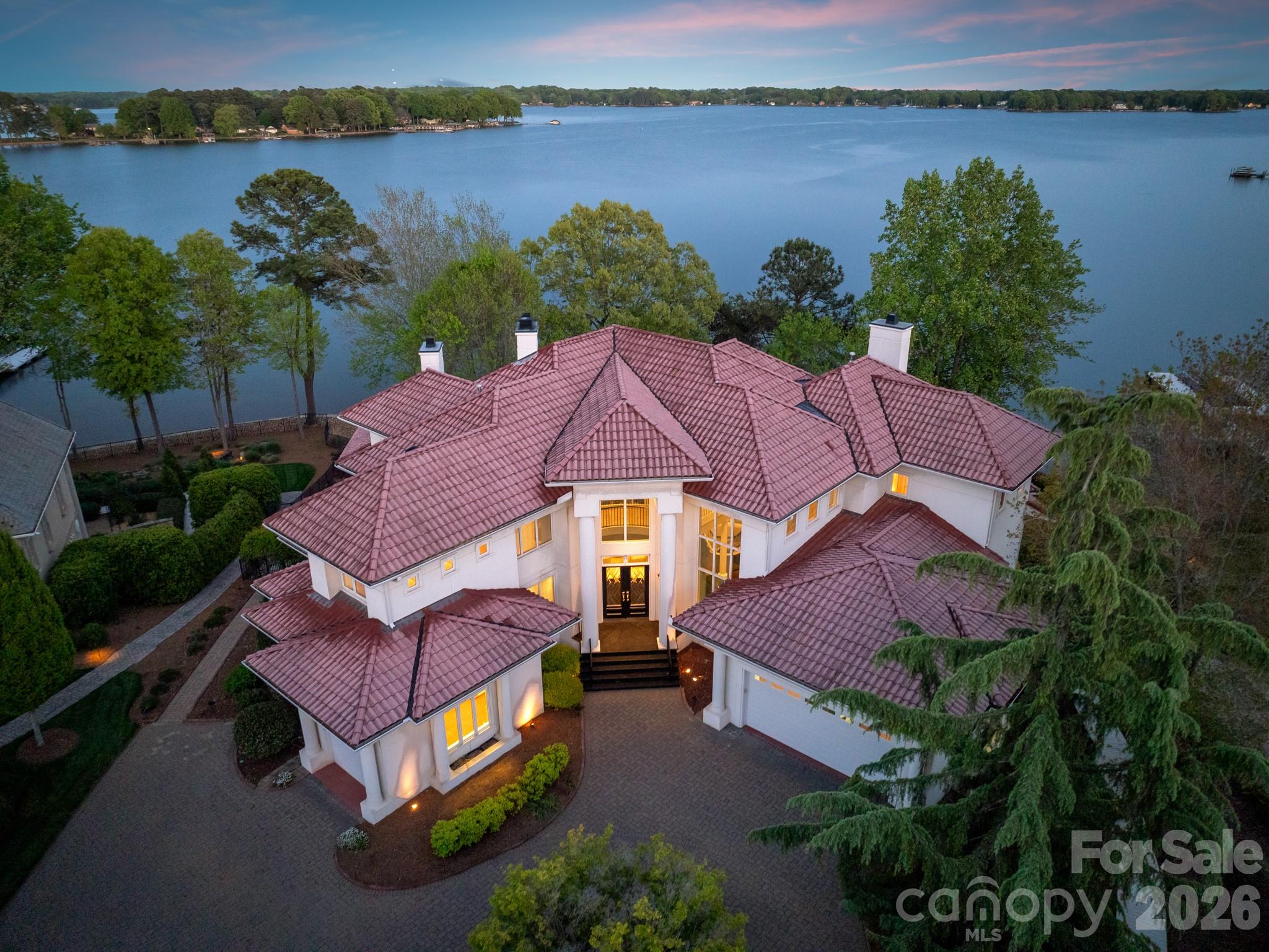 Commanding the shores of Lake Norman, this breathtaking 5BR, 8BA waterfront estate in The Point offers resort-style living for the global buyer seeking privacy, prestige, and panoramic views. Spanning over 7,300 sq ft, the home features soaring ceilings, a grand spiral staircase, chef’s kitchen with fireside lounge, and a lower level designed for entertaining with a theater, wine cellar, full bar, and lounge. Lake-facing suites open to expansive decks for seamless indoor-outdoor living. Outdoors, enjoy a heated pool, spa, fire pit, outdoor kitchen, and covered terrace. A private dock with a boat and two jet ski lifts completes this extraordinary offering. This is timeless Southern elegance with a modern edge—just 40 minutes from Charlotte Douglas International Airport. A rare opportunity to own one of the region’s most exclusive waterfront estates.