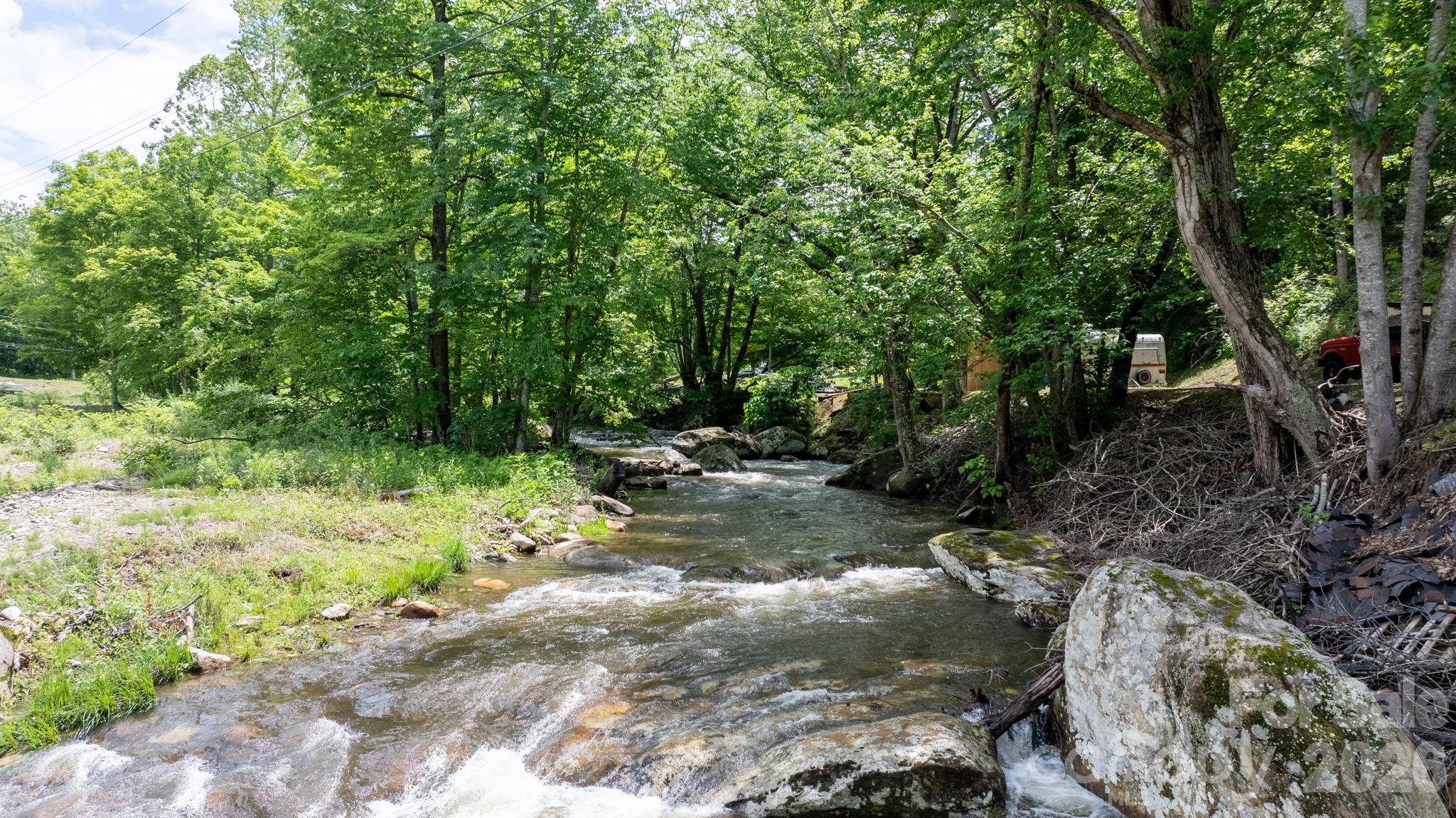 The sound of Little Rock Creek sets the tone for life at this mountain cabin retreat, where rushing water, mature trees, and scenic valley views create a setting that feels miles away from the pace of everyday life. Relax on the screened porch overlooking the creek, listen to the water flow over the rocks below, and enjoy the natural beauty that surrounds the property year-round.

This home is just a short drive to Roan Mountain, which straddles TN & NC and has a summit of 6,285 feet! There you'll find high-elevation views, and some of the best hiking and biking trails you'll ever find! The iconic Appalachian Trail takes you over several well-known balds offering 360-degree panoramic views! Spend time at the Willis Observatory for stargazing, deep-space astrophotography, and other out of this world activities. 

Inside, the 3-bedroom, 2-bath home blends rustic character with thoughtful updates. A fully remodeled kitchen features custom countertops and all-new appliances, while the dramatic vaulted living room showcases soaring ceilings, wood floors, and a stone fireplace that anchors the heart of the home. An upstairs bedroom opens to a private balcony, offering another peaceful spot to take in the surrounding landscape. 

Apple and pear trees add seasonal charm to the property, while the outdoor living spaces make it easy to enjoy the sights and sounds of the creek. Whether you're looking for a full-time residence, mountain getaway, or investment opportunity, this property offers a unique combination of comfort, character, and an exceptional creekside setting, close to so many amazing attractions and activities.