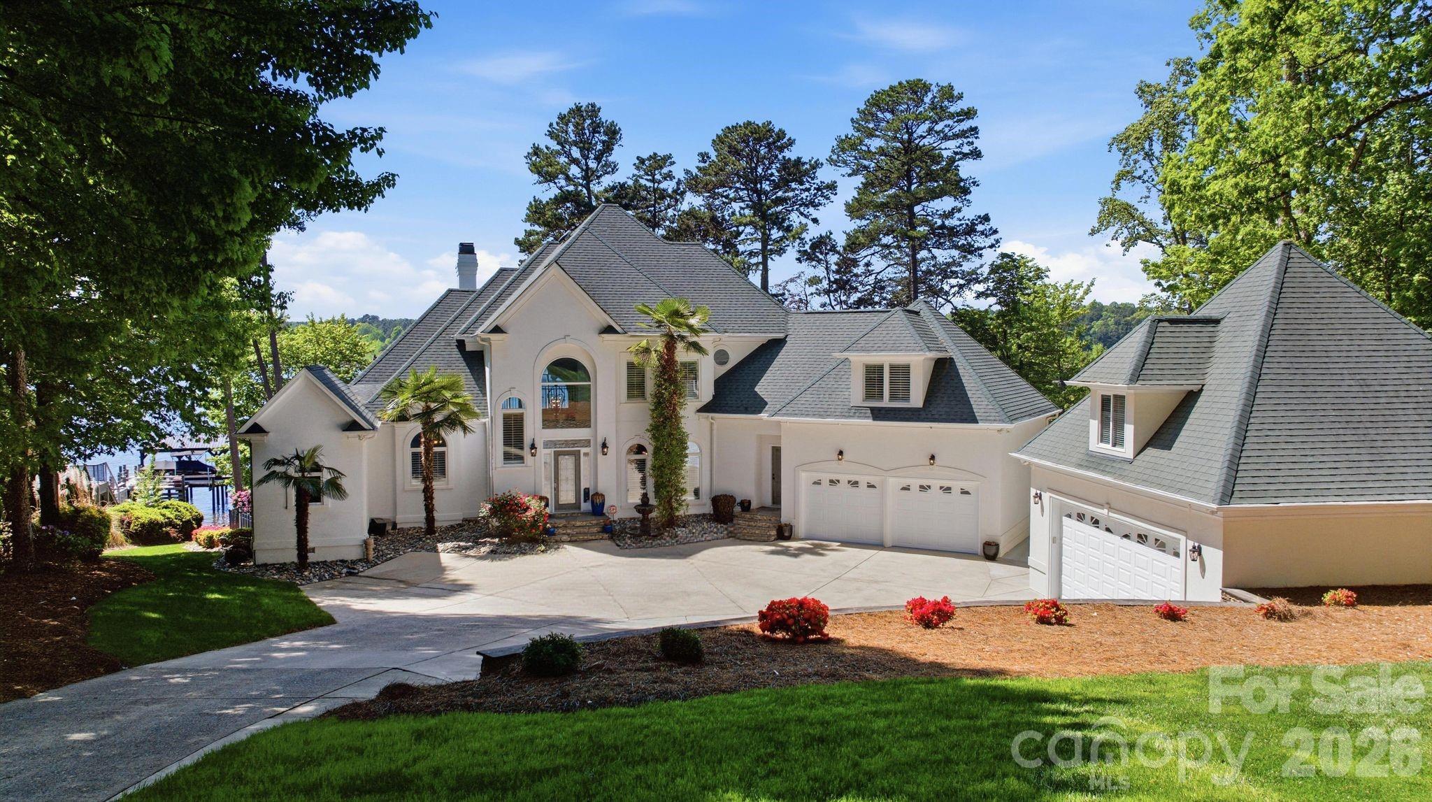 Positioned on nearly an acre along the shores of Lake Norman, this exceptional waterfront estate is thoughtfully oriented to capture breathtaking west-facing sunset views. A rarity among homes on the lake, this premier positioning creates a seamless connection to the outdoors, filling the interiors with natural light throughout the day and culminating in unforgettable sunsets each evening.

Spanning over 4,700 square feet, the home offers five bedrooms and a thoughtfully designed layout ideal for both everyday living and elevated entertaining. The main level begins with a grand two-story foyer that opens into an impressive great room with soaring ceilings, a stone fireplace, and custom built-ins, all overlooking the lake. A formal dining room with arched windows flows seamlessly into a well-appointed kitchen featuring premium appliances, generous cabinetry, and a central island, along with an inviting breakfast area. The main-level primary suite serves as a private retreat with a lounge area, spa-inspired bath, expansive custom closet, and direct access to the covered outdoor patio. A spacious laundry room and effortless indoor-outdoor flow complete the main level.

Upstairs, three well-appointed guest suites offer comfortable accommodations, complemented by two full bathrooms and flexible living space.

The lower level is designed for entertaining and relaxation, featuring a large entertainment room with fireplace and bar, along with an additional bedroom, a secondary living area, and a full bath. A covered patio extends the living space outdoors, leading to the resort-style pool and landscaped grounds.

Outdoor living is equally compelling, with multiple covered terraces, integrated audio, heaters, and a fire pit. All thoughtfully positioned to take full advantage of the home’s western exposure and stunning sunset backdrop. The private dock with dual boat lifts and a covered lounge creates the ultimate lakefront experience, offering front-row seats to some of Lake Norman’s most picturesque evenings.

Additional highlights include both an attached two-car garage and a detached two-car garage, along with extensive upgrades throughout. Located in the heart of Mooresville, just minutes from dining, shopping, and marinas, this home offers a rare blend of luxury, functionality, and truly exceptional west-facing sunset views over Lake Norman.