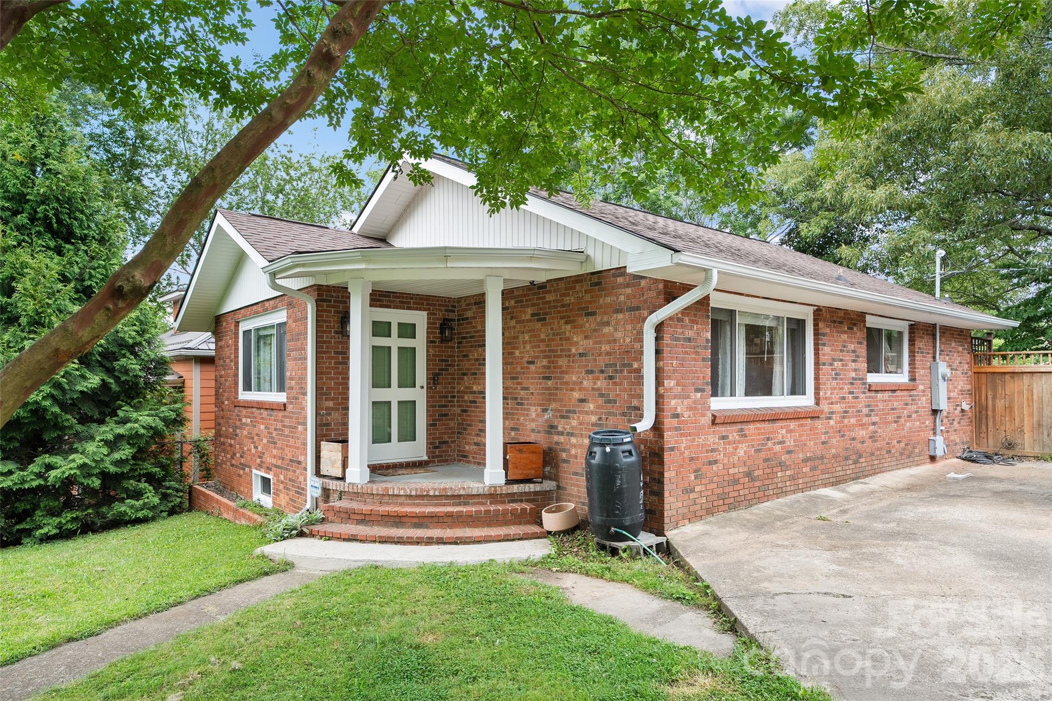 There’s something special about a classic West Asheville bungalow—the kind of home that feels welcoming the moment you arrive. The feeling begins beneath the canopy of a magnificent historic oak tree, a timeless centerpiece that gives this property its unmistakable character and charm. Just minutes from Haywood Road, Carrier Park, and downtown Asheville, this move-in-ready home blends classic appeal with thoughtful updates. Natural light fills the inviting living spaces, highlighting beautiful hardwood floors and creating a warm, comfortable atmosphere. The kitchen offers updated finishes, ample storage, and everyday functionality, while the renovated bathroom adds a fresh, modern touch. Designed for easy one-level living, the floor plan is both practical and welcoming. Outside, the fenced backyard and spacious patio provide the perfect space for entertaining, gardening, or relaxing under the shade of the property's stunning oak tree. Walk to Asheville's favorite restaurants, breweries, parks, and greenways, this home offers the perfect combination of charm, comfort, and location.