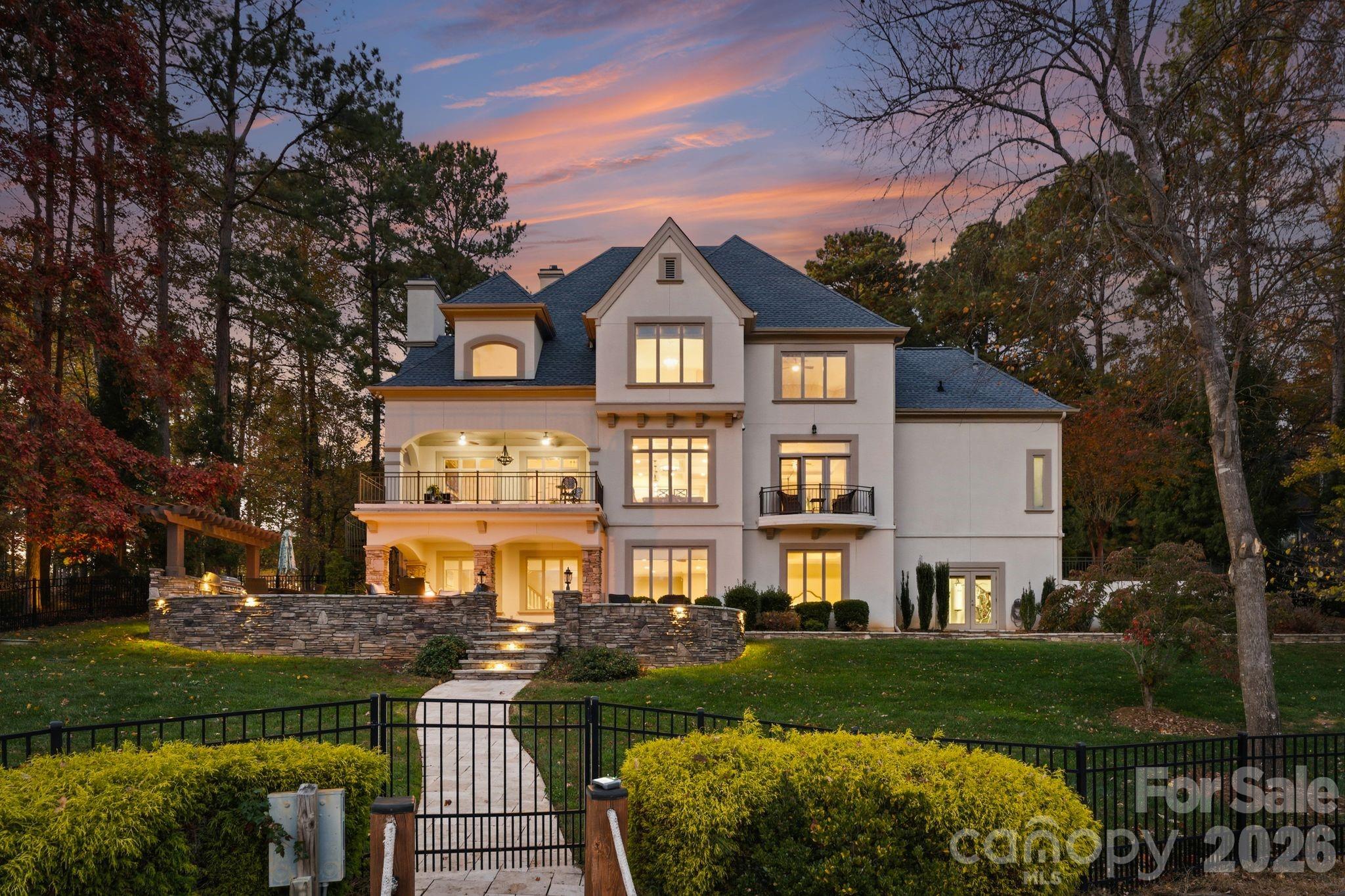 Experience the pinnacle of Lake Norman living in this stunningly reimagined estate, perfectly positioned within the prestigious community of The Point at Trump National Golf Course. This meticulously maintained stucco and stone residence has been transformed into a private resort experience, blending sophisticated modern updates with an unmatched waterfront lifestyle. The exterior serves as a true sanctuary, featuring a rare private sandy beach and a newly rebuilt dock complete with a dedicated sitting area and boat lift. Whether you are hosting on the expansive new balcony finished with Montalcino porcelain tile or relaxing on the travertine patio by the outdoor kitchen and hot tub, the home is designed to maximize its commanding water views and exceptional privacy. 

The interior reflects a commitment to high-end design, beginning with an inviting foyer that leads to an executive office featuring a gas fireplace and an elegant coffered ceiling. The heart of the home opens into a soaring two-story great room with a floor-to-ceiling stone fireplace and abundant natural light. The upscale kitchen is a culinary showpiece, featuring stylish quartz counters, coffered ceilings, and a premium appliance suite including a Wolf cooktop, double oven, and a built-in microwave drawer. This space flows seamlessly into the breakfast area and a formal dining room serviced by a refined butler’s pantry.

The main-level owner’s suite serves as a luxurious retreat, offering a private Juliet balcony overlooking the lake and a newly completed spa-like bathroom. This sanctuary is outfitted with dual quartz vanities, a sleek glass shower, a soaking tub, and elegant herringbone tile floors with radiant heating. Upstairs, the home continues to impress with new hardwood flooring throughout, three spacious bedrooms with updated baths, a large bonus room, and a versatile loft space perfect for a home workstation.

The walk-out lake level is an entertainer’s dream, featuring an expansive family room anchored by a cozy fireplace and a fully equipped second kitchen and bar. This level also includes a billiard area, plenty of storage for lake essentials, and a dedicated theater room for cinematic experiences at home. Wellness is prioritized with a private exercise room and sauna, alongside a fifth guest bedroom. This property has been curated for those seeking the ultimate in gracious lakefront living, complete with a whole-house generator installed in 2024 for total peace of mind.