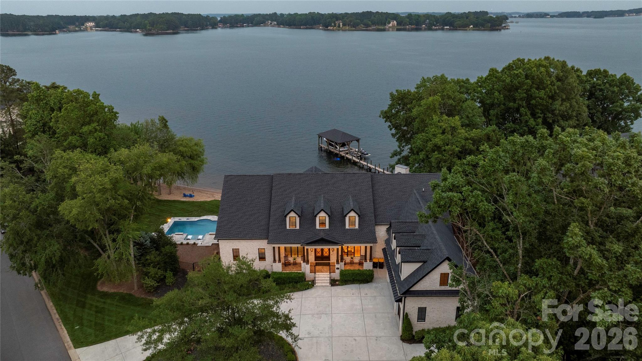 Luxury lakefront living awaits on Lake Norman. Perfectly positioned on an over-an-acre cul-de-sac lot with 295 feet of shoreline, including 100 feet of rare natural white-sand beach, this exceptional waterfront estate offers sweeping panoramic water views that stretch for miles and deliver breathtaking sunrises in the morning and historic sunsets that paint the sky in the evening. The backyard oasis, enhanced by over $1M in recent upgrades, rivals a private resort, featuring a stunning pool, expansive hardscaping, a cozy fire pit, and a beautifully constructed rock seawall—all designed to maximize the extraordinary waterfront setting. Spanning 9,434 square feet, the home offers 5 bedrooms and 5.5 baths, including two primary suites and an elevator serving all three levels, making it ideal for extended family or guests. Inside, expansive rooms, soaring ceilings, and walls of windows frame the lake from nearly every angle, filling the home with natural light and creating a seamless connection between indoor and outdoor living. Designed for both everyday living and entertaining, the chef’s kitchen features double islands, a 48” Thermador range, a Thermador wall oven with microwave, a True refrigerator, freezer, and wine refrigerator, a beverage station with beverage refrigerator, a coffee bar, and a large walk-in pantry. This extraordinary residence blends thoughtful design, modern luxury, and unmatched waterfront beauty—a rare opportunity to own one of Lake Norman’s most spectacular lakefront retreats. Conveniently located near shopping and dining. 45 minutes to Uptown Charlotte and 30 minutes to the Douglas International Airport.