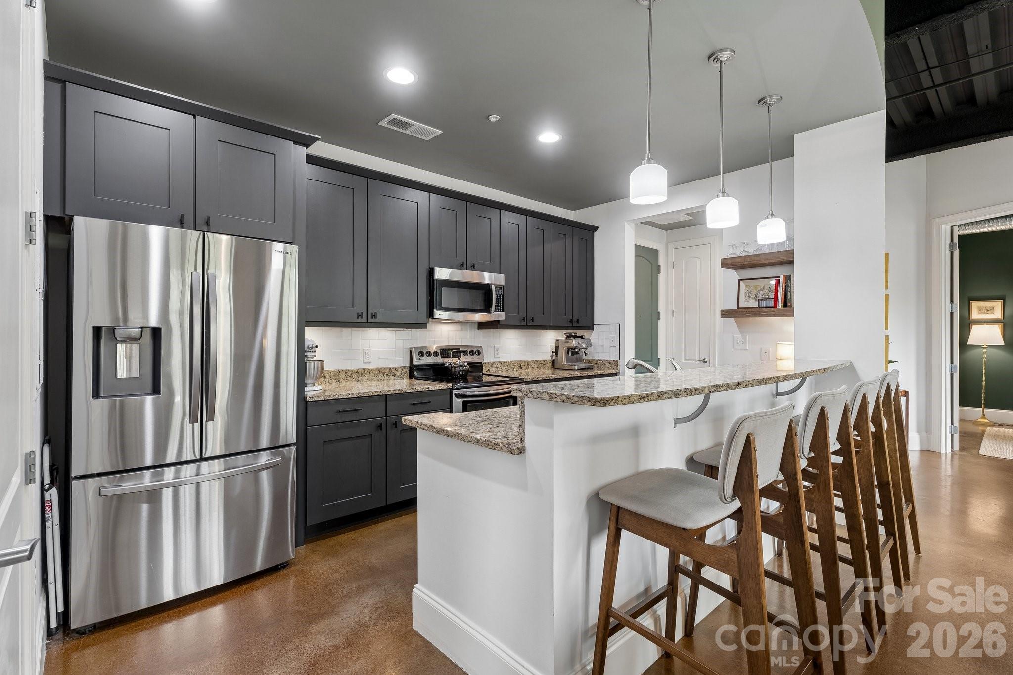 Live where Charlotte comes alive! This ultra-cool industrial modern condo places you in the heart of NoDa and Villa Heights, two of the Queen City’s most vibrant, walkable, and culture-rich neighborhoods. With soaring 10-foot ceilings, exposed beams, concrete floors, and an open, sun-filled layout, this 2-bedroom, 2-bath condo delivers effortless style with a true urban edge.
Step into a modern open kitchen featuring granite countertops, sleek dark cabinetry with generous storage, a subway tile backsplash, and oversized bar seating perfect for entertaining. The spacious living area flows seamlessly into a quaint dining space overlooking a private balcony with views of the grassy area below, ideal for morning coffee or unwinding after a day in the city.
The guest bath has been tastefully updated with Farrow & Ball wallpaper, wainscoting, and an updated vanity and mirror. The versatile guest bedroom includes a built-in Murphy bed that conveys, making it the perfect multi-purpose space for guests, a home office, or both.
The primary suite features a walk-in closet, private en suite bath, and its own Juliet balcony. Enjoy unbeatable rooftop access with stunning Uptown skyline views, along with nearby pet-friendly green spaces.
From this central location, you are just steps from NoDa’s popular bars, breweries, restaurants, coffee shops, galleries, and entertainment, with easy access to Optimist Hall, The Hobbyist, The Degenerate, Rhino Market, Amélie’s, Villa Heights, Plaza Midwood, South End, and the LYNX Blue Line for a quick ride Uptown.
This stylish, low-maintenance, move-in-ready home offers the perfect blend of convenience, character, and vibrant city living.
