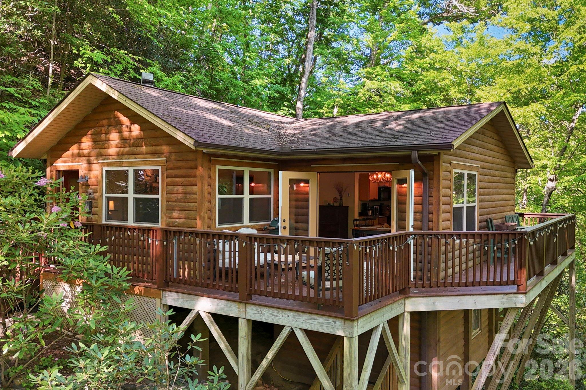 This enchanting Cabin and Guesthouse nestled in the trees overlook a roaring stream and the storybook hamlet of Cattail Creek. The private 1/2 acre lot adjoins a 615 acre parcel to the south that is part of the 13,000+ acre conservation of Mount Mitchell State Park. Less than an hour drive from downtown Asheville and less than 20 minutes from downtown Burnsville, the property feels a world away from the stress of everyday life while maintaining modern needs w/ high speed fiber internet. The main cabin offers an open floorplan w/ vaulted ceilings, hardwood floors, large living area with woodstove & natural stone surround, and a spacious kitchen & dining area w/ double doors to a large wraparound deck w/ mountain & creek views. The generous bedroom w/ ensuite bathroom opens onto a screened porch w/ sounds of the creek lulling you to sleep. The room allows for a king size bed and desk area along w/ 2 closets, one a walk-in that has been used as a kid sleeping nook. A stone path meanders from the main cabin past covered wood storage to the Bunkhouse w/ it's own large deck providng an additional bedroom/bathroom for guests or studio/flex space. The cabin's lower level contains the laundry room and plenty of additional storage/work/flex space. This is a true oasis for nature lovers, immersed in the sounds of water and woods w/ plentiful hiking trails nearby.