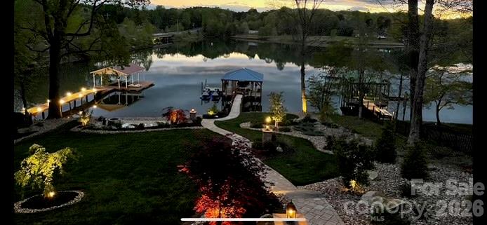 PRICED BELOW APPRAISAL – FULLY FURNISHED– TURNKEY WATERFRONT WITH DOCK + SUNSET VIEWS ON LAKE NORMAN

Welcome to a luxury waterfront residence on Lake Norman, offering a rare combination of refined interior upgrades, highly functional outdoor living, An exceptional opportunity to secure a fully furnished, move-in ready waterfront home positioned on open water with a private dock and sunset-facing views—now offered below appraised value. Walk-out lower level offers significant expansion potential—ideal for adding living space, guest suite, or increasing overall value. Property offers potential for future detached garage/guest suite addition (subject to buyer verification and permitting), creating an opportunity to further expand functionality and value.

Built in 2018 and significantly upgraded beyond builder standards, this property delivers the rare combination of condition, location, and immediate usability that today’s buyers are searching for.
Vaulted ceilings and expansive windows frame wide lake views and fill the open-concept living space with natural light. The kitchen is designed for both everyday living and entertaining, featuring River Marble flooring, upgraded granite, and premium appliances including a Bosch dual-fuel range, warming drawer, Bosch dishwasher, and LG refrigerator. The oversized peninsula creates a seamless flow into the dining and living areas, anchored by a gas fireplace and direct access to a sunroom overlooking the water.
Hickory hardwoods extend throughout the main living areas and bedrooms. The primary suite captures lake views and offers functional convenience with direct access to the laundry room. Interior finishes include crown molding, custom window treatments, and well-appointed baths with a soaking tub.
Outdoor living is where this property separates itself. A maintenance-free deck with a fully equipped outdoor kitchen and electric awning overlooks the lake, while professionally designed landscaping—with over 100 tons of river rock—creates a polished, low-maintenance setting. A lighted pathway leads to a lakeside patio with fire pit and down to the private dock.
The covered dock includes an 8,000 lb boat lift, sun pad, and dual jet ski ports—ideal for immediate lake use or short-term rental income potential.
Additional features include a whole-home generator, 10x12 storage building, and walk-in basement with partially finished bath offering expansion potential. No HOA.
Offered fully furnished for a true turnkey experience.
Ideal as a full-time residence, second home, or investment property with strong rental appeal.
Opportunities like this—priced below appraisal, fully furnished, and ready for immediate enjoyment—are limited on Lake Norman. Schedule your showing today.