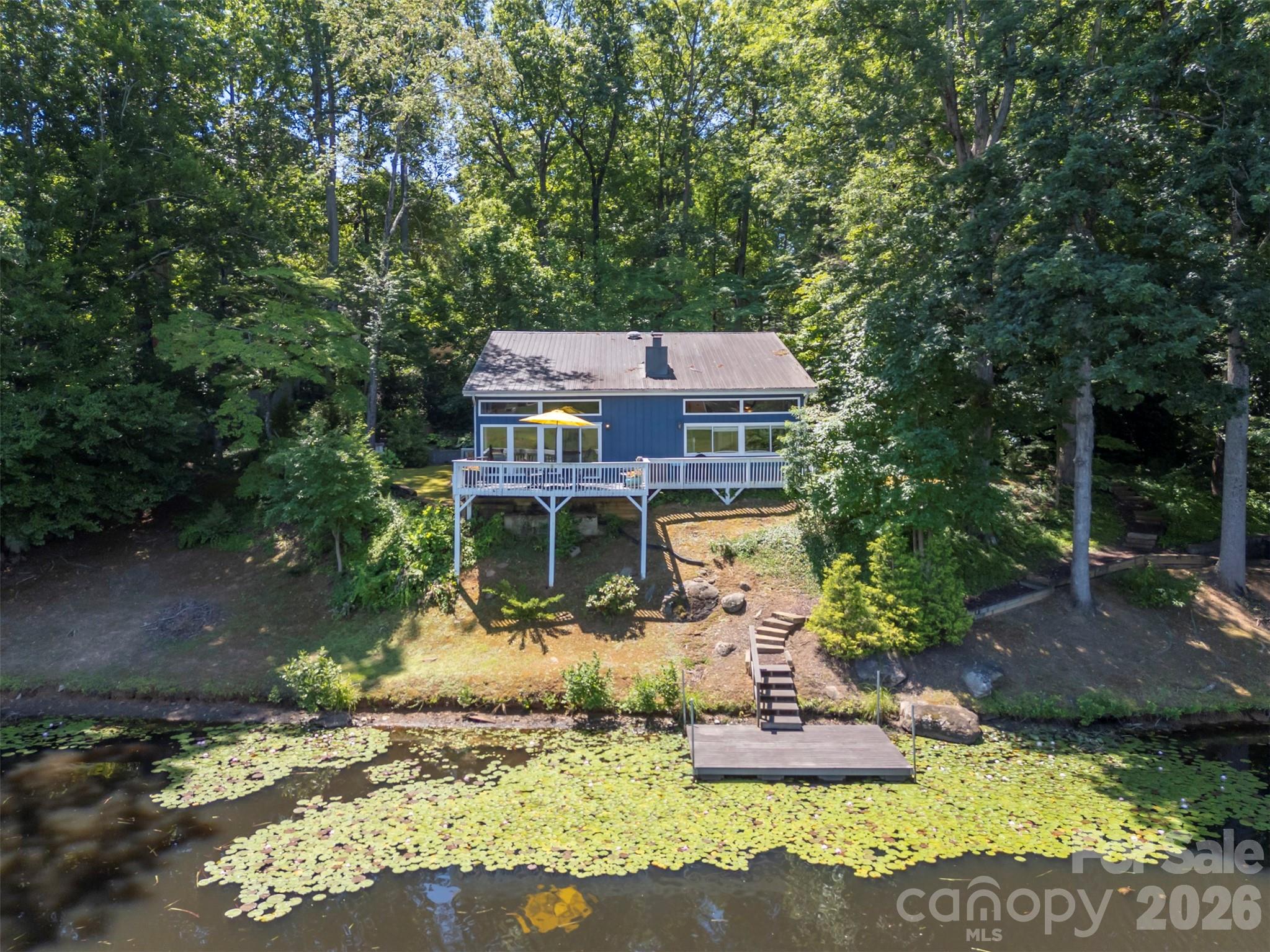 Lakefront Living on Forest Lake – Privacy, Charm & Convenience! Welcome to this beautiful 3-bedroom, 2 full bath lakefront home nestled on nearly an acre in the desirable Forest Lake Acres Subdivision. Situated on a private 0.96-acre lot with mature shade trees, this property offers a peaceful retreat while remaining just minutes from downtown Forest City. Inside, you'll find a warm and inviting floor plan filled with natural light thanks to the abundance of windows throughout the home. The spacious primary suite is conveniently located on the main level and features a private en-suite bath. Upstairs, two generously sized bedrooms provide plenty of room for family, guests, or a home office. The stunning brick fireplace serves as a focal point of the living area, creating the perfect gathering space year-round. Step outside onto the deck overlooking Forest Lake and enjoy tranquil water views, morning coffee, or evening sunsets. Follow the path to the water's edge, where a floating dock provides easy access to the lake for fishing, kayaking, or simply soaking in the surroundings. A lakeside firepit creates the perfect setting for relaxing evenings under the stars.  Additional features include a two-car carport with a large storage closet, ample outdoor space, and the option to purchase the home furnished—making it move-in ready or an excellent vacation getaway opportunity. Conveniently located within 5 minutes of downtown Forest City, the Thermal Belt Rail Trail, shopping, dining, and local attractions, this lakefront gem combines privacy, comfort, and accessibility in one exceptional package!