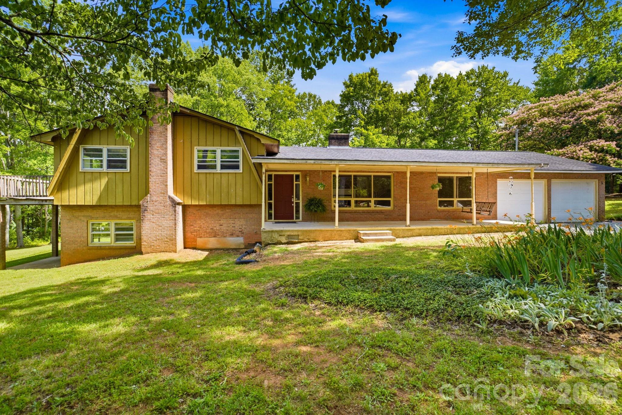 Set on over 5 private acres, this split-level home with basement offers 4 bedrooms, 2.5 baths, and 2,907 square feet of flexible living space designed for those seeking a true rural lifestyle with room for horses, hobby farming, or a small homestead vision. The property includes approximately 25,000 sq ft of tillable ground that can serve as pasture or garden space, surrounded by mature hardwoods that provide privacy and a peaceful, natural setting. Fresh paint throughout and new LVP flooring across both the main and lower levels create a clean, updated feel while preserving original character details like decorative plaster ceilings. The main level includes a living room, dining area, kitchen, and a spacious great room designed for everyday living and gathering. The kitchen features original wood cabinetry with opportunity to update into a custom farm-style space. Multiple heat sources including a pellet stove, wood-burning insert, and fireplace provide comfort in every season. Upstairs, flexible bedroom spaces accommodate family, guests, or office use, with both the primary and secondary bedrooms opening to a deck overlooking the land. The lower level and basement expand the living potential with a second kitchen, a bath in progress already plumbed for completion, a potential second living area, and over 1,000 sq ft of stand-up storage ideal for tack, feed, or equipment. Outdoor living includes five porches and patios with a screened-in porch, front porch with swing, multiple seating areas, and fire pit spaces. A classic outbuilding adds workshop or barn-style flexibility, with additional storage structures across the property. Muscadine vines and established garden areas enhance the homestead feel. A recorded easement along the left side provides access to a neighboring parcel. A rare opportunity to create your ideal horse property, hobby farm, or private rural retreat while still remaining convenient to everyday amenities.
