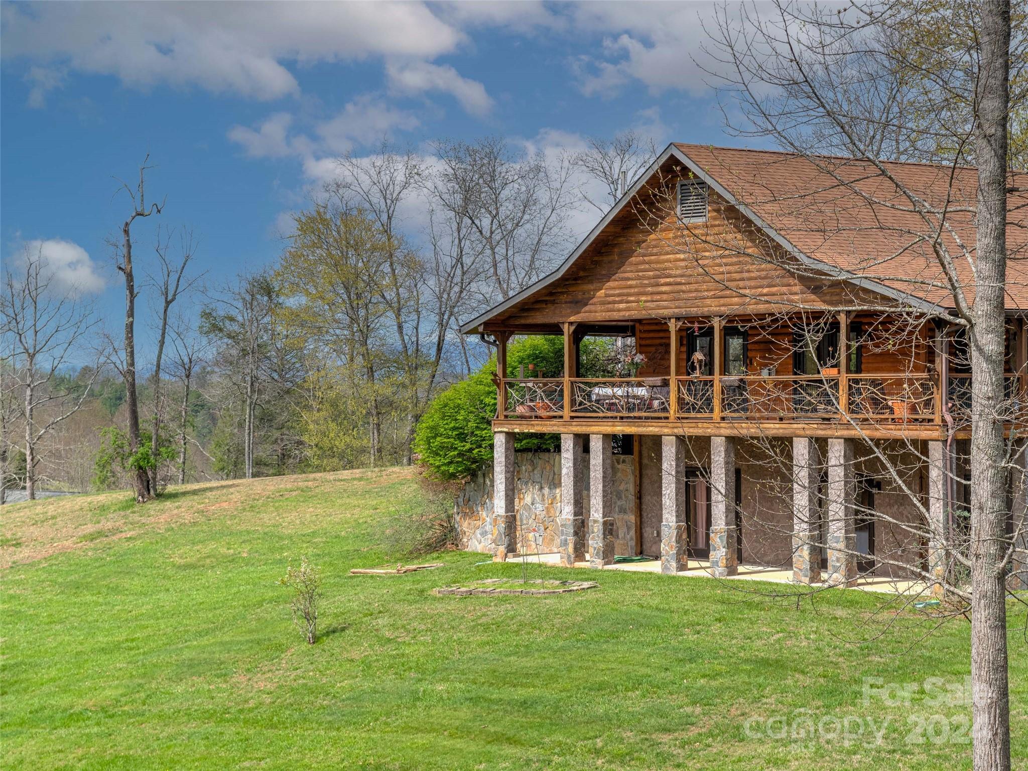 Quintessential log home in a highly desirable community only steps away from the center of the town of Bakersville. This gorgeous lodge is perfect for the person seeking a log home with mountain views, a usable yard, and the convenience of living close to town. The home features wood floors, a gas log fireplace, a new HVAC unit, a new dishwasher, and a new door-in-door Fridge. The primary suite with a laundry chute in the bathroom makes this home ideal for main-level living. Enjoy sitting under one of six fans on the spacious porch, which wraps around three sides of the home. Take time to appreciate the fragrant wisteria on the additional deck's pergola. Downstairs you will find two guest bedrooms, each with patio access. Full bathroom, laundry room, and exterior parking access give guests some privacy. Mature landscaping, a street light at the driveway entrance, and a community pond with a party gazebo. If you seek adventure, you are a short drive from Roan Mountain State Park.