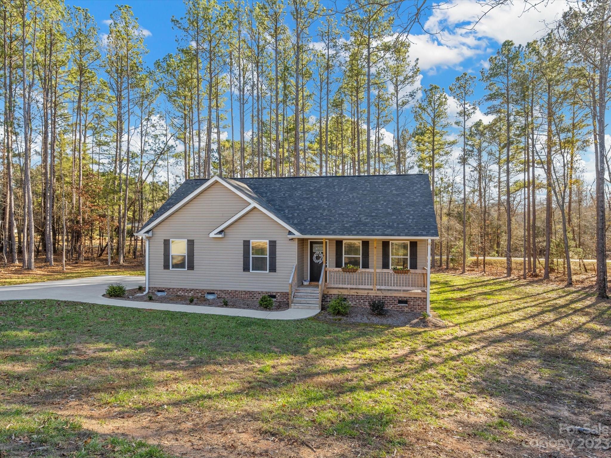 This practically new home is 100% move in ready! The cute covered front porch welcomes you.  Inside you'll find LVP flooring and carpet in the bedrooms.  The kitchen includes a breakfast bar with granite counter tops, SS appliances, and soft close cabinets and drawers.  The laundry room boasts a walk-in pantry or utility closet, with extra room for a freezer or storage. Bedrooms have spacious closets.  Out back you'll love the covered porch, with a view of the wooded lot.  This home sits on over an acre and has plenty of space to add a garage or park your RV or boat.  Bonus: there is NO HOA.