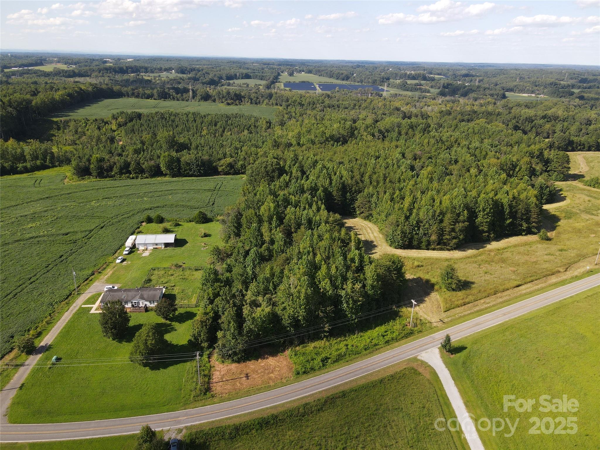 Unique property in East Iredell area. This 15+ acre tract has just at 100' of road frontage on Rowan Road. The acreage contains trees over approximately 65% of the property.  It extends back over 1/2 mile to a larger area that is currently in crops. An ideal mini-farm location with most of the workable area being in the 100' (99'.71 ft)wide area that opens up in the rear and offers perfect opportunity to construct barn, add livestock, fence and other desired agricultural uses.   Also could be a great hunting and recreational area The acreage in the rear of the tract is in a 100 year flood plain and contains a steel tower with overhead transmission lines and a noted R/W. Survey attached.  One seller is a NC licensed real estate agent. Rowan Road is state-maintained.