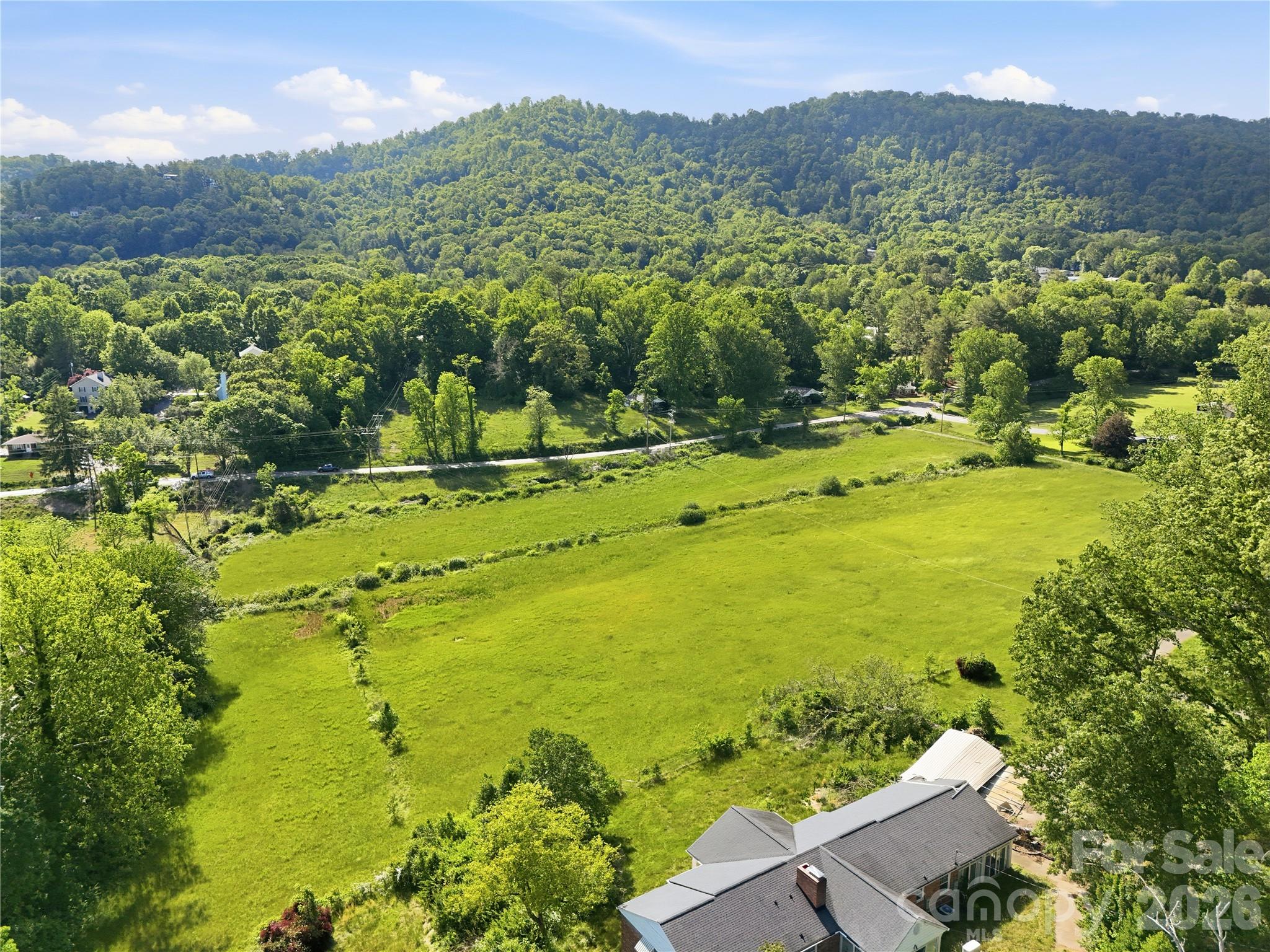 25+ acres of exceptionally usable, buildable land in highly desirable Haw Creek — an increasingly rare opportunity in Asheville. This unique estate-sized property offers an extraordinary combination of cleared pasture and meadow areas, expansive lawn space, mature woods, and gentle rolling topography that is easy to walk, and easy to build on. Large tracts with this kind of terrain, privacy, flexibility and convenience to Downtown Asheville are nearly impossible to find.   Whether you envision a private family estate, luxury home compound, multi-generational retreat, or future subdivision opportunity, the property offers outstanding potential. Multiple possible homesites enjoy a beautiful natural setting with a blend of open and wooded landscapes.     The existing five older single-family homes, with some updating and repairs, will provide additional flexibility for rental income, guest accommodations, caretaker housing, or temporary use while planning future improvements. All five homes feature newer roofing, updated plumbing, and circuit-breaker panel boxes. A separate two-bay mechanic’s shop with tall bay doors and its own electrical service adds even more utility to the property.    Current zoning is "conditional" and base zoning is RS4. Buyer to confirm all information.  Seller is executor of estate, has limited knowledge of the property, and has never occupied the premises.