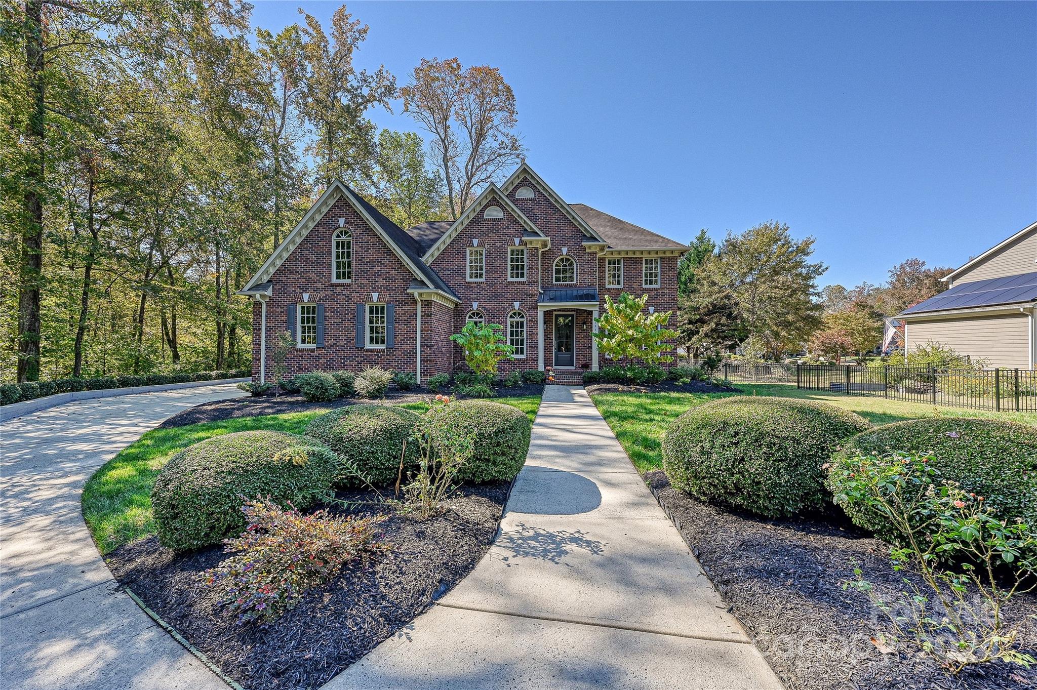 RARE RURAL RETREAT WITH URBAN CONVENIENCE! Nestled just outside downtown Davidson on a protected half-acre lot, this all-brick home radiates charm and elegance with serene, park-like surroundings. Thoughtfully set back, the expansive front yard offers ample separation from the road and includes a side-load garage, parking pad, and spacious driveway, perfect for parking, toy storage, or DIY projects. Enhanced privacy is assured by forest and wetland borders that prevent future development. Inside, hardwood floors flow into a cozy living room with a striking stone fireplace, an eat-in kitchen with granite countertops and stainless appliances, and a main-level guest bedroom with full bath. The primary suite overlooks a fenced, low-maintenance backyard—ideal for pets and play. Relax in the custom three-season porch, or gather around a fire pit in the side yard. Conveniently located near shopping, dining, historic Davidson, with proximity to Cornelius, Birkdale, top schools, and no HOA.
