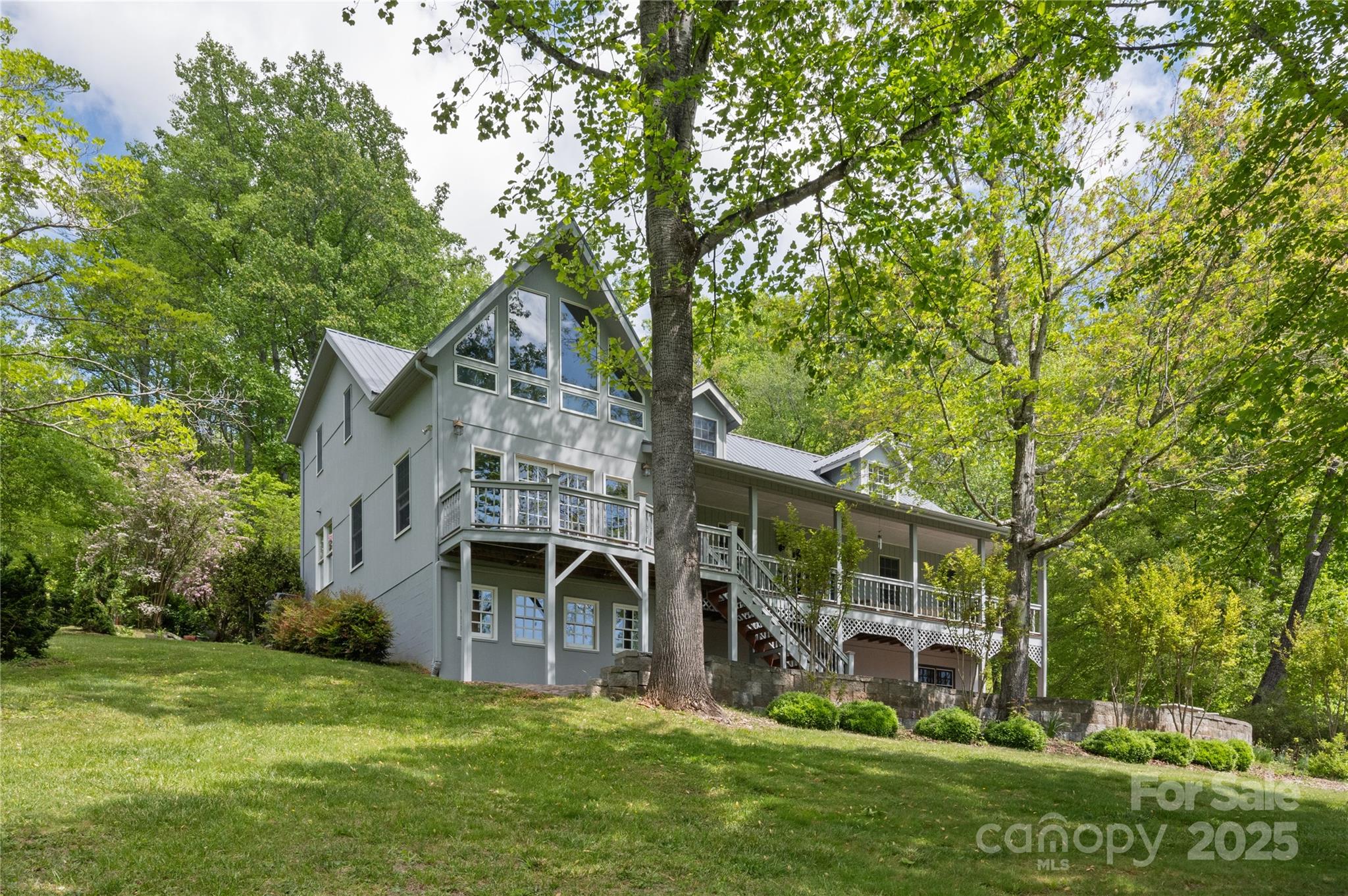 This stunning estate home sits perched upon its gentle acreage down a quiet road in Candler. Relax while breathing in the crisp mountain air. Enjoy views from your pick of covered porches. Mature plantings, specimen trees, seasonal blooms, and multiple fresh water springs will surely delight! Perhaps you will choose to catch dinner in stocked pond? You will love the large detached garage, barn, and multiple storage sheds. Inside find extra-large rooms with expansive windows, hand crafted moldings, and gleaming hardwood floors. The robust wood stove and custom built, energy efficient, Isokern fireplace are sure to keep you cozy and warm when the temperatures drop. Upstairs, there is a 546 Sq foot flex room/studio space with an outside entrance, and the daylight walk-out basement has an expansive workshop and office space. There is even a walk-in vault for valuables, whether those be collectibles or provisions. What a rare offering of a legacy property!