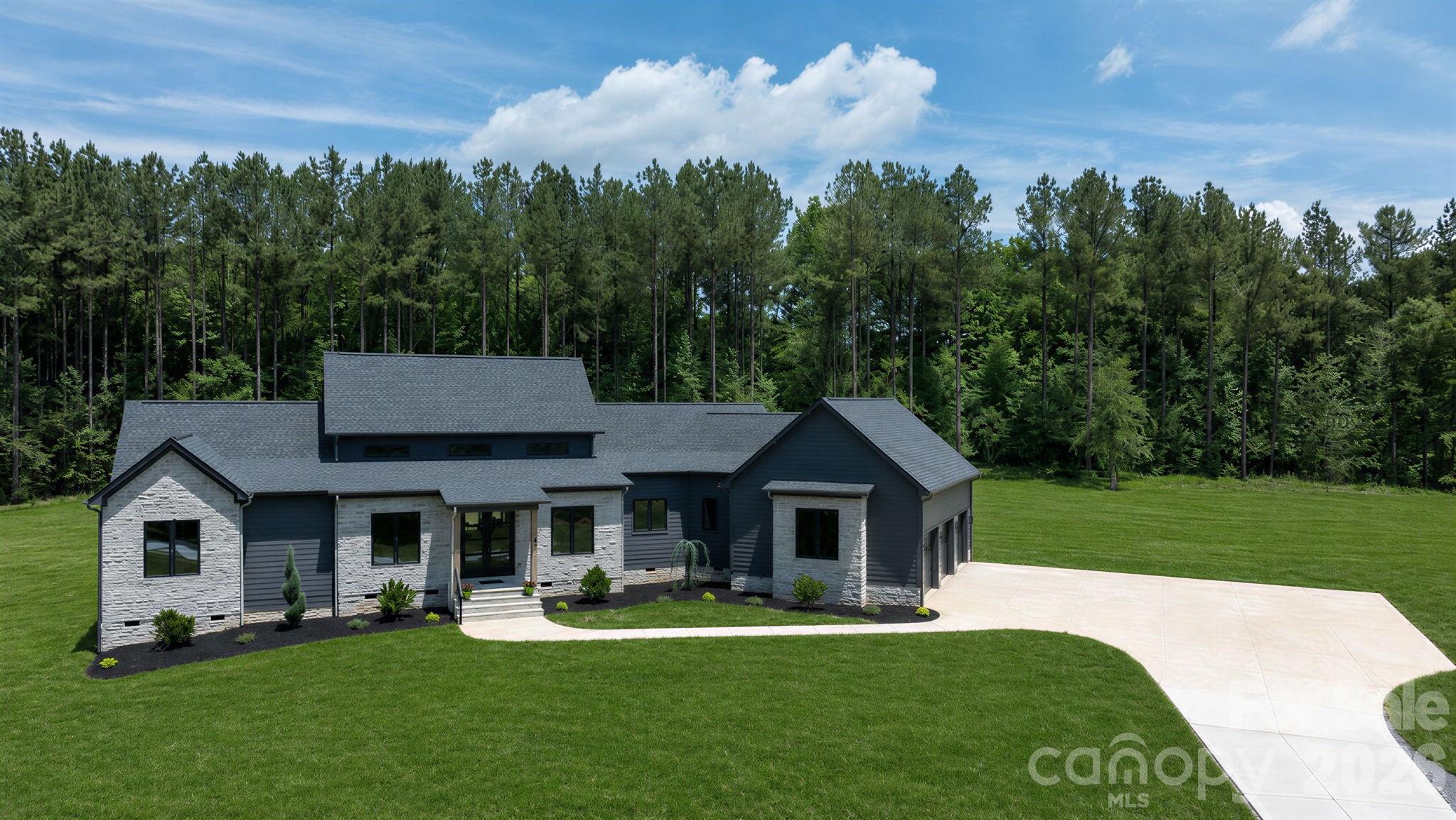 We are so excited to welcome you to 1427 Glasscock Road! Tucked away at the end of a scenic 900-foot driveway, this beautiful 24.42-acre retreat offers a wonderful sense of peace and privacy; where the possibilities are endless!
This new construction modern ranch home was designed with connection in mind, featuring a bright, open layout perfect for entertaining. The spacious  modern kitchen boasts taj mahal countertops, a breakfast island, and a walk-in scullery, with sliding doors that open seamlessly to a patio and outdoor kitchen.
Wake up in peaceful master suite overlooking a wooded yard, a hidden flush mount motorized TV for movies on demand, the a spa-like 10ft ceiling bathroom has a rain shower, heated tile floors, LED smart touch fogless mirror and a clever walk-through closet connected to the laundry for easy access. Enjoy a cozy en-suite bathrooms and walk-in closets for each bedroom. For both work and leisure, this home features a dedicated office and a media or and library room pre-wired for surround sound. The spacious living room also includes built-in speakers with surround sound ideal for movie nights.. Park your car in a spacious vaulted ceiling 3 car garage; which doors open vertical making room for car lifts with electric car charging station as a thoughtful and exceptional design. Limitless potential for a yard that's prewired for a barn, shop, pool or anything you'd like!
Just 30 minutes from uptown charlotte, with no HOA this beautiful estate could be the perfect place for you!
All offers submit to Rock Hill Charm Development LLC.