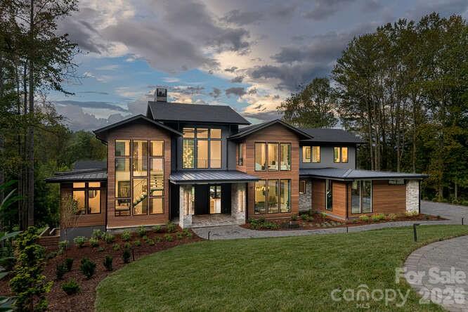 Welcome to 39 Bear Flower Trail—an exceptional newly constructed estate by Buchanan Construction, honored with four distinguished awards including the coveted Gold Craftsmanship Award. Set within the prestigious, gated enclave of The Cliffs at Walnut Cove—home to a PGA Tour venue for the next four years—this 8,200± sq. ft. mountain modern residence represents the pinnacle of refined living in Western North Carolina.

Thoughtfully designed with architectural precision and timeless elegance, the home offers 6 bedrooms, 7 full baths, and 2 half baths, creating a private sanctuary for both everyday living and elevated entertaining. A dramatic steel floating staircase anchors the grand entry, while soaring ceilings and expansive walls of glass frame sweeping mountain vistas and bathe the interiors in natural light.

The main living spaces unfold seamlessly, defined by impeccable craftsmanship, curated finishes, and a striking floor-to-ceiling fireplace. The open-concept design effortlessly transitions to outdoor living, creating a harmonious connection between interior sophistication and the surrounding natural beauty.

A collection of resort-caliber amenities enhances the experience of living well: a private theater, an expansive recreation lounge with full wet bar, a temperature-controlled wine cellar, and a dedicated wellness suite featuring a fully equipped fitness studio and sauna. Every space has been meticulously curated to deliver both comfort and understated luxury.

The outdoor living environment is equally compelling—featuring a resort-style pool and spa, a fully appointed outdoor kitchen, and a private pool bath—offering an extraordinary setting for entertaining or quiet retreat amid the Blue Ridge Mountains.

Located within one of the Southeast’s most sought-after communities, residents enjoy unparalleled access to world-class golf, dining, wellness, and security—delivering a lifestyle defined by privacy, prestige, and effortless luxury.