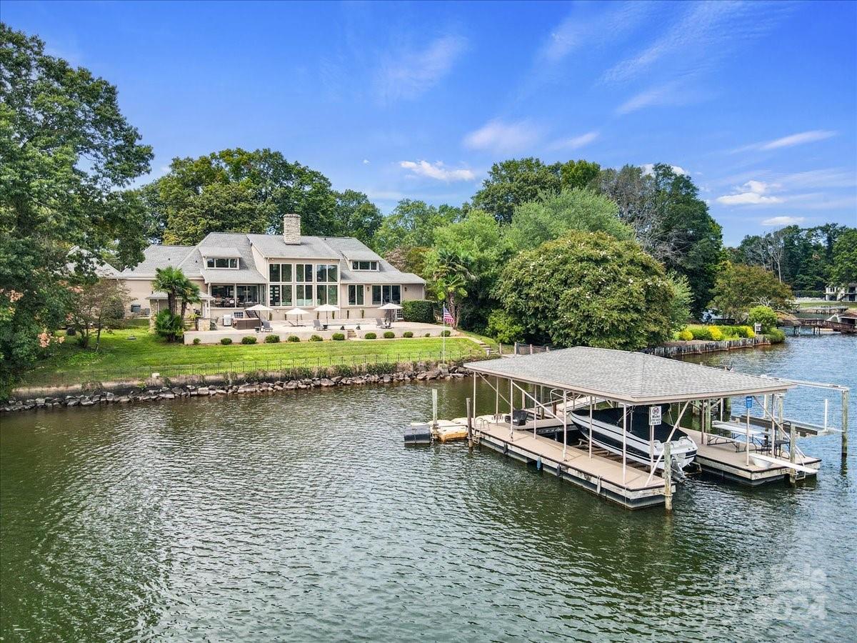 Experience unparalleled lakeside living in this stunning 3-bedroom, 3-bath home in Denver, NC, located on a peaceful cul-de-sac. This open-concept gem features a chef’s kitchen that flows effortlessly into the spacious living room and sunroom, where a dramatic see-through fireplace adds warmth and charm. Floor-to-ceiling windows frame breathtaking lake views, seamlessly blending indoor elegance with outdoor beauty. The main floor hosts a luxurious primary suite with a private bath, offering a tranquil retreat. Step outside to your very own pool overlooking the serene lake, perfect for relaxation and entertaining. The oversized dock includes a covered boat area and 2 boat lifts and a watercraft ramp for up to 4 PWC for convenient access to the water. With a 2-car attached garage and a 2-car detached garage, this home provides ample space for both vehicles and storage, embodying the ultimate blend of modern comfort and waterfront luxury. Please see attached feature sheet!
