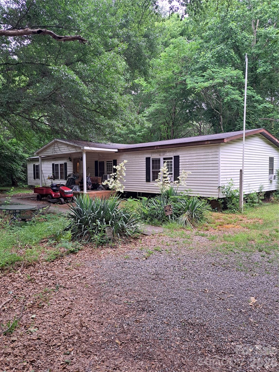 Doublewide on acreage in Stanley, NC, with road frontage along Mauney Road and a corner lot at Dogwood Lane. The property features a mix of flat and rolling terrain, a creek at the back, and potential public sewer access near the creek with an extension. Included is an 1,800 sq ft manufactured home (built in 1989) with a split-bedroom floor plan: the primary bedroom and main bath are on the left, while secondary bedrooms and another full bath are on the right. The central great room boasts ceilings and a corner wood-burning fireplace with stone veneer. The kitchen includes a center island with a stovetop and range hood. The home is served by a 6-inch well and septic system, with county records with location sketch available. Electrical has 200Amp Service.  Updates needed include flooring, a heat pump system, a perimeter foundation curtain wall, and possibly a new roof, though no active leaks are visible. Land near Mauney Road was once pasture but is now overgrown with young trees. Dogwood Lane is a private drive maintained by local residents. Soil reports, topo maps, and sewer engineering maps are available. Also listed as land under MLS #4365671
