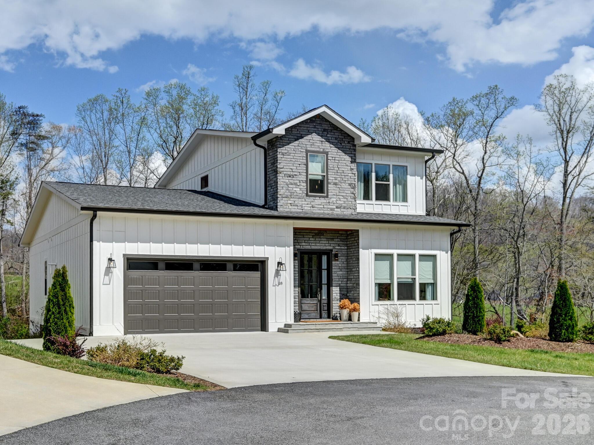 Welcome to easy mountain living at 18 Sagewood Drive. Tucked at the end of a cul-de-sac in Stoneridge at Hayes Mountain, this 2022-built home offers a quiet setting in Candler with Asheville just a short drive away. Shopping, dining, entertainment, and everyday essentials are all within easy reach, giving you the perfect balance of privacy and convenience. Inside, the bright open-concept main level is designed for comfortable daily living and effortless entertaining. The living room, dining area, and kitchen flow seamlessly together, while large windows fill the space with natural light and frame seasonal mountain views. The kitchen features generous cabinetry and ample counter space, making meal prep simple while keeping everyone connected. The spacious primary suite on the main level offers a private retreat with a walk-in closet and en-suite bath. Upstairs bedrooms are well-sized and flexible for guests, hobbies, or additional living space. Laundry connections on both levels add everyday convenience, while an office and separate study area provide valuable flexibility for remote work, reading, or creative pursuits. Step outside to the covered rear porch and enjoy the peaceful neighborhood setting. The manageable lot offers outdoor enjoyment without the burden of constant upkeep. 18 Sagewood Drive combines modern comfort, low-maintenance living, and a mountain setting while remaining close to the vibrant restaurants, shopping, entertainment, and amenities of Asheville. If you’ve been looking for a peaceful place to call home near the city, this is the one. Schedule your showing today!