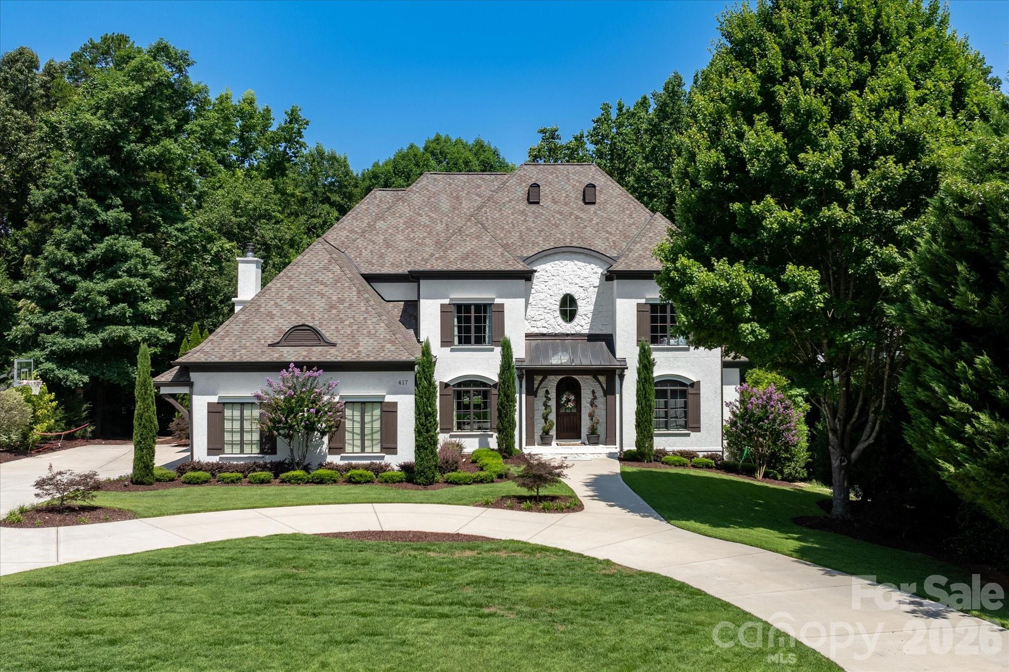Welcome to one of Springfield's most distinguished residences, where timeless European architecture and thoughtfully curated interior spaces come together to create an extraordinary living experience. Nestled on a beautifully landscaped homesite, this custom-built estate offers a rare combination of elegance, comfort, and modern sophistication.

Grand living spaces on three levels are designed for both everyday living and exceptional entertaining. The stunning great room serves as the heart of the home, showcasing soaring vaulted ceilings accented by exposed beams, custom built-in cabinetry, rich hardwood floors, and a dramatic fireplace that creates an inviting yet refined atmosphere. Natural light pours throughout the home, highlighting impeccable craftsmanship and designer finishes at every turn.

The chef's kitchen features premium appliances, generous workspace and seamless flow into gathering and dining areas—perfect for intimate family dinners or hosting on a grand scale. The luxurious main level primary suite offers a private retreat complete with tray ceiling and serene views of the surrounding landscape.

Ascending to the second level, you'll discover a continuation of rich hardwood flooring; three spacious guest bedrooms, two elegantly appointed full baths, and a dedicated built-in study area designed for today's lifestyle.

Designed with versatility in mind, the home's expansive lower level provides exceptional additional living space ideal for an in law suite with full bath and kitchen; media room/recreation area, full Gym/fitness studio, and entertaining venue.

Outside, manicured grounds and mature landscaping create a private sanctuary for the inground pool/spa. Spacious Upper and lower Terraces and a fireplace for all your entertaining needs.

Springfield lifestyle—where an 18 hole Public golf course, Included resort-style amenities (Clubhouse; fitness center; 3 pools;Tennis and pickleball courts; playground; pocket parks etc), and access to the Anne Springs Close Greenway create one of the Charlotte region's most coveted living experiences.