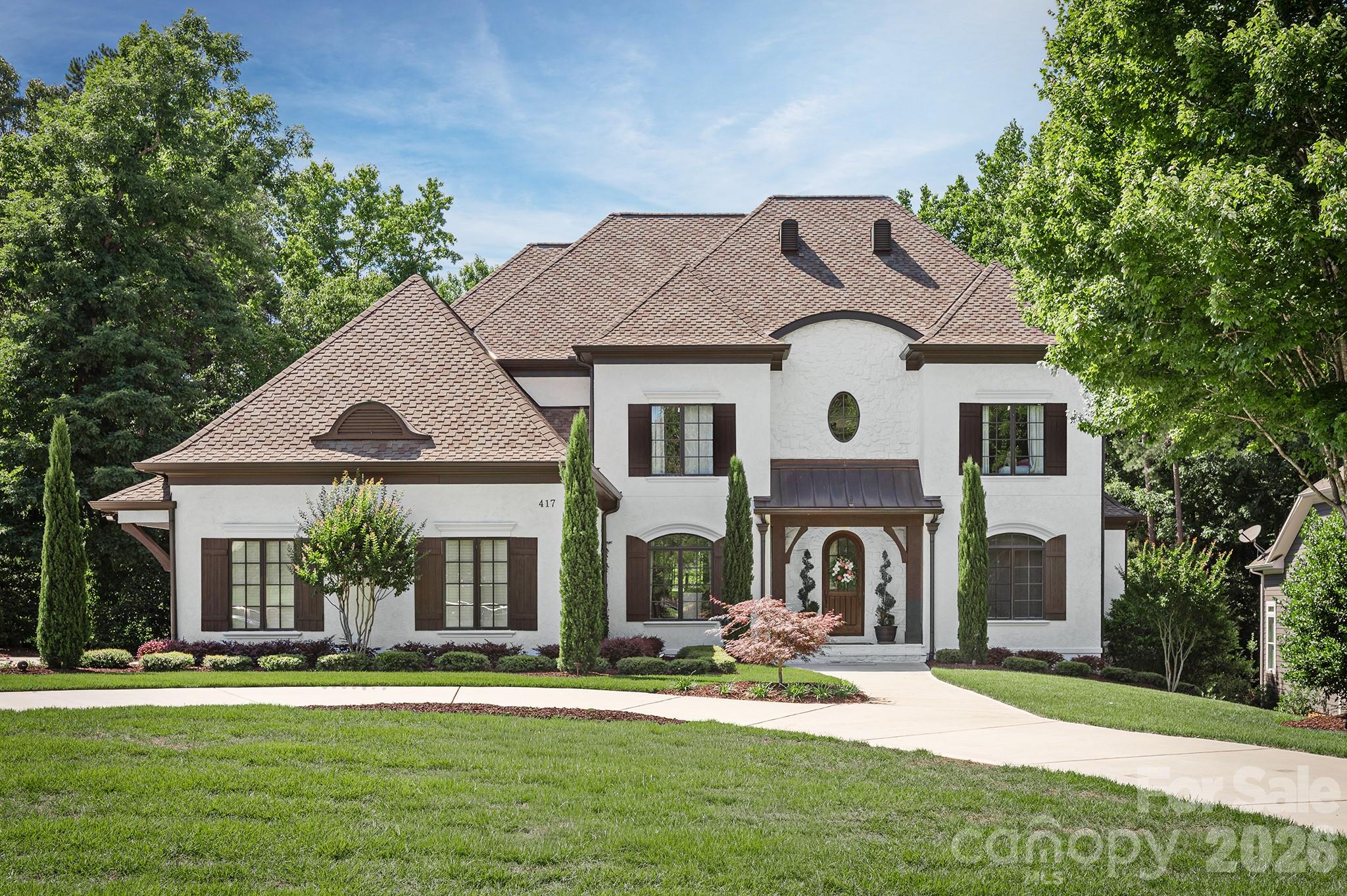 Welcome to one of Springfield's most distinguished residences, where timeless European architecture and thoughtfully curated interior spaces come together to create an extraordinary living experience. Nestled on a beautifully landscaped homesite, this custom-built estate offers a rare combination of elegance, comfort, and modern sophistication.

Grand living spaces on three levels are designed for both everyday living and exceptional entertaining. The stunning great room serves as the heart of the home, showcasing soaring vaulted ceilings accented by exposed beams, custom built-in cabinetry, rich hardwood floors, and a dramatic fireplace that creates an inviting yet refined atmosphere. Natural light pours throughout the home, highlighting impeccable craftsmanship and designer finishes at every turn.

The chef's kitchen features premium appliances, generous workspace and seamless flow into gathering and dining areas—perfect for intimate family dinners or hosting on a grand scale. The luxurious main level primary suite offers a private retreat complete with tray ceiling and serene views of the surrounding landscape.

Ascending to the second level, you'll discover a continuation of rich hardwood flooring; three spacious guest bedrooms, two elegantly appointed full baths, and a dedicated built-in study area designed for today's lifestyle.

Designed with versatility in mind, the home's expansive lower level provides exceptional additional living space ideal for an in law suite with full bath and kitchen; media room/recreation area, full Gym/fitness studio, and entertaining venue.

Outside, manicured grounds and mature landscaping create a private sanctuary for the inground pool/spa. Spacious Upper and lower Terraces and a fireplace for all your entertaining needs.

Springfield lifestyle—where an 18 hole Public golf course, Included resort-style amenities (Clubhouse; fitness center; 3 pools;Tennis and pickleball courts; playground; pocket parks etc), and access to the Anne Springs Close Greenway create one of the Charlotte region's most coveted living experiences.