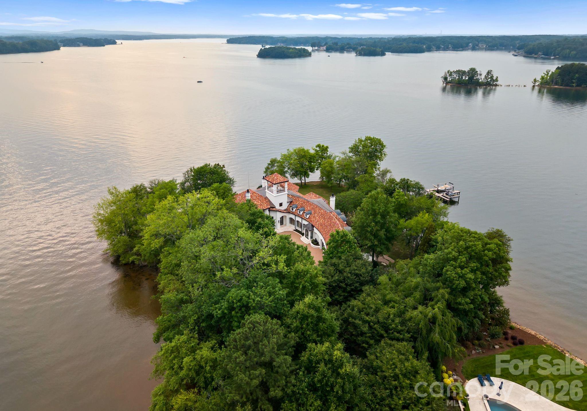 Welcome to Puesta del Sol... A Rare Waterfront Sanctuary with 938’ of Pristine Shoreline on Lake Norman — where ELEGANCE meets EXCLUSIVITY. Nestled on a private gated peninsula, this estate offers 938 feet of shoreline & panoramic lake views from every level & bedroom! Inside, light-filled spaces, curved walls, designer finishes, & a gourmet kitchen set the tone for effortless luxury. The main-level primary suite offers luxurious bedroom, dual closets, and separate shower & spa-like bath. Take the elevator to the second level boasting 2nd primary suite plus 3 additional spacious en-suite bedrooms, theater, billiard room, and exercise space. End or begin the day on the rooftop covered terrace with stunning sunrise & sunset vistas. The outdoor spaces are equally impressive: pool and spa, private pier with a dock, boat lift equipped with electric Swiftshield cover & jet ski lifts. This is more than a home — it’s a rare lifestyle opportunity on one of North Carolina’s most desirable lakes.