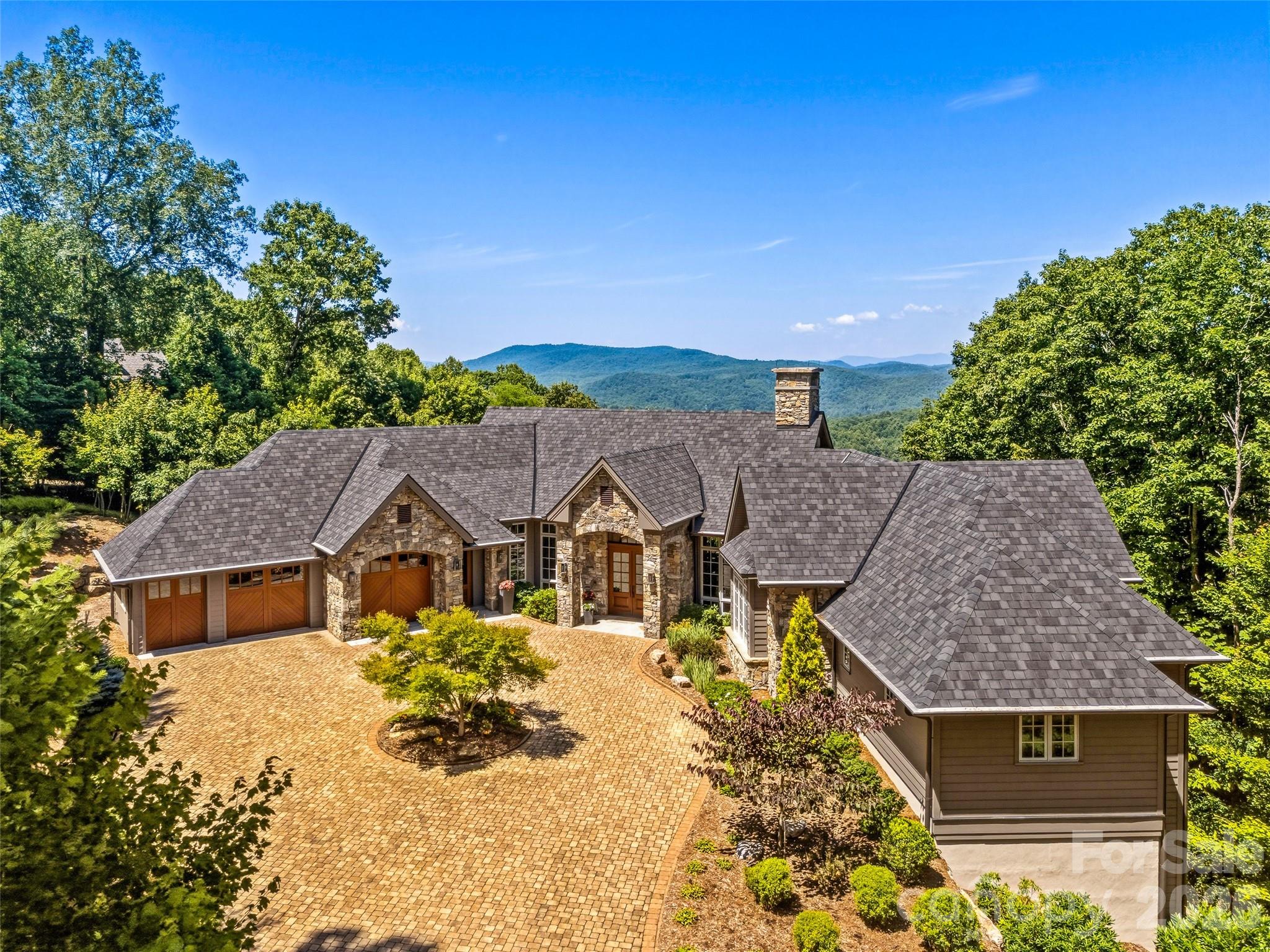 Welcome to 504 Hagen Dr. An extraordinary expression of mountain luxury, this Energy Star Certified custom estate is thoughtfully positioned on a private one-acre homesite in Champion Hills, where sweeping western mountain views, timeless architecture, and elevated design create a residence that is as sophisticated as it is inviting. Just 10 minutes from historic downtown Hendersonville, this home offers the perfect balance of serene mountain living and everyday convenience.

Crafted with impeccable attention to detail, the stone and timber exterior opens to interiors defined by soaring beamed ceilings, dramatic walls of windows, hand-scraped Chateau Oak flooring by Burchette & Burchette, and solid alder doors throughout. The open floor plan was designed for gracious entertaining and effortless everyday living, with every room intentionally oriented to capture natural light and breathtaking Blue Ridge vistas.
At the heart of the home, a chef's kitchen appointed with Sub-Zero and Wolf appliances, including an induction range, convection oven, steam oven, and beverage chiller—flows seamlessly into expansive gathering spaces and onto the 484-square-foot all-season screened porch. Complete with a retractable vinyl rain protection system, natural gas grill, and fire table, this remarkable indoor-outdoor living space invites year-round entertaining, whether hosting sunset dinners with friends or enjoying quiet mornings overlooking the mountains.
Framed by soaring ceilings and dramatic walls of windows, the Great Room is anchored by a self-playing baby grand piano, creating an unforgettable setting for intimate evenings and elegant gatherings alike.
The main-level primary suite is a private sanctuary featuring dual spa-inspired bathrooms with heated floors, generous walk-in closets, and refined finishes throughout. Two dedicated offices provide exceptional flexibility for today's lifestyle, while dual pantries, an oversized seasonal storage room, and an oversized two-car garage with a dedicated golf cart bay offer the thoughtful conveniences that define luxury living. The lower level features two spacious guest suites and a welcoming family room, allowing family and friends to enjoy their own private retreat.

Designed with wellness, efficiency, and peace of mind in mind, the home is Energy Star Certified and equipped with a four-zone Energy Recovery Ventilation (ERV) system, dual Trane natural gas furnaces with HEPA filtration and humidifiers, whole-house charcoal water filtration, two Rinnai tankless water heaters, radon mitigation, lightning protection, whole-home generator, and poured concrete foundation.
Modern technology is seamlessly integrated through Josh AI voice control, a comprehensive Control4 automation system, programmable Lutron lighting, Category 6 wiring, whole-home audio and Wi-Fi distribution, elevator access to every level, EV charging pre-wire, Flologic leak detection, and seven-zone irrigation—allowing every comfort to be managed effortlessly.

Every detail has been carefully curated to create a home that feels both luxurious and livable. Here, sophisticated design, exceptional craftsmanship, and the beauty of the Blue Ridge Mountains come together to offer a lifestyle that is truly without compromise. Optional Champion Hills Club membership provides access to Tom Fazio championship golf, exceptional dining, fitness, tennis, pickleball, and one of Western North Carolina's premier private club communities.