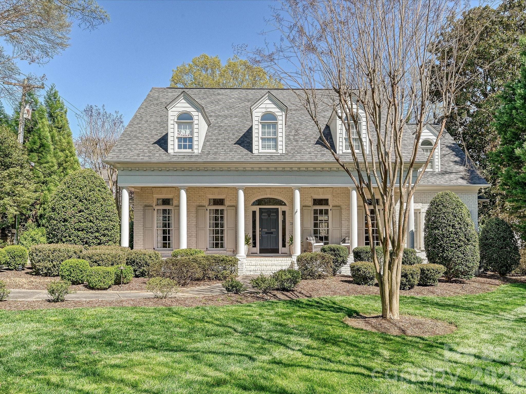 Beautiful white painted brick 1.5-story home on a flat, manicured lot with timeless curb appeal and an ideal layout. A welcoming foyer opens to the living and dining rooms with 10 foot ceilings. The great room features built-ins flanking the fireplace and a full wall of glass doors overlooking the back porch, filling the home with natural light. A wide arched openings lead to the lovely updated kitchen with white cabinetry, marble countertops, bar seating, and a sunny breakfast nook. The serene primary suite is located on the main level with a large ensuite bath, and walk-in closet. Front and rear staircases lead upstairs to 3 secondary bedrooms, 2 full baths plus a large bonus room. A fifth bedroom and full bathroom is also tucked upstairs privately at the back of the home—ideal for guests, a nanny suite, in-law suite, or flex space. Hard to find rear attached 2-car garage adds everyday ease. Welcome home!