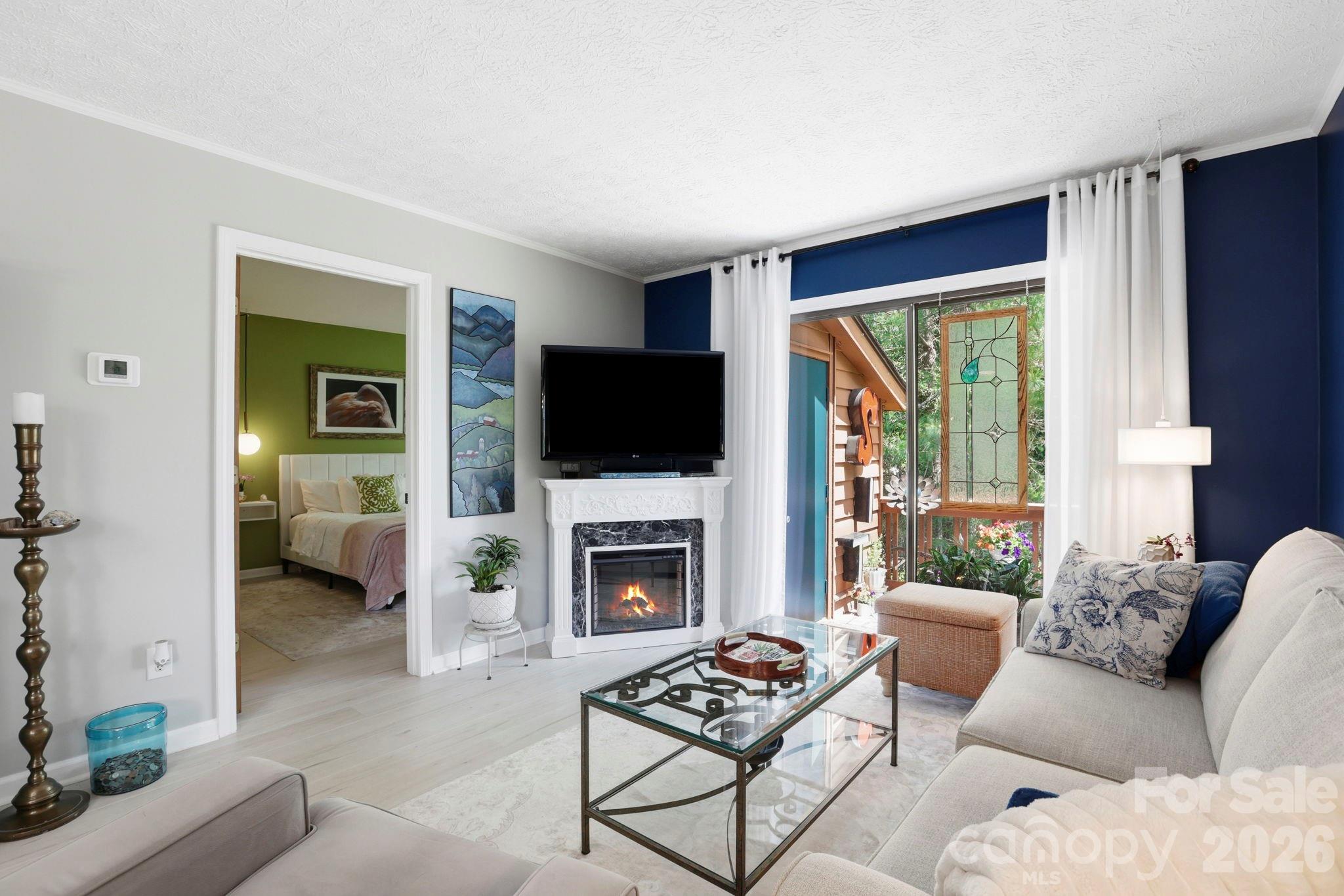 Welcome to this upper-level, two-bedroom, one-full-bath, one-half-bath condominium offering the perfect blend of privacy, personality and low-maintenance living. Positioned at the quiet end of the community, one of the most coveted locations in the development, the home captures distant year-round mountain views from the dining area and overlooks beautifully maintained flower gardens. Inside, the residence has been thoughtfully updated with bold design choices, including a deep navy accent wall and light engineered-wood-style flooring. Sliding glass doors open from the living area onto a private deck, an ideal spot for morning coffee surrounded by a mature tree canopy. The kitchen features white cabinetry and pendant lighting, while the dining area is brightened by a statement chandelier. Recent mechanical upgrades include a new roof, gutters, an HVAC and a water heater, a few years young, which provides genuine peace of mind, and HOA dues are paid through December 2026. All of this sits just minutes from Downtown Hendersonville, the Ecusta Trail, Historic Flat Rock, Flat Rock Playhouse, the Carl Sandburg Home, Pardee Hospital and AdventHealth, with Downtown Asheville only 30 minutes away. A rare opportunity to own a distinctive, move-in-ready home with character and convenience in equal measure.