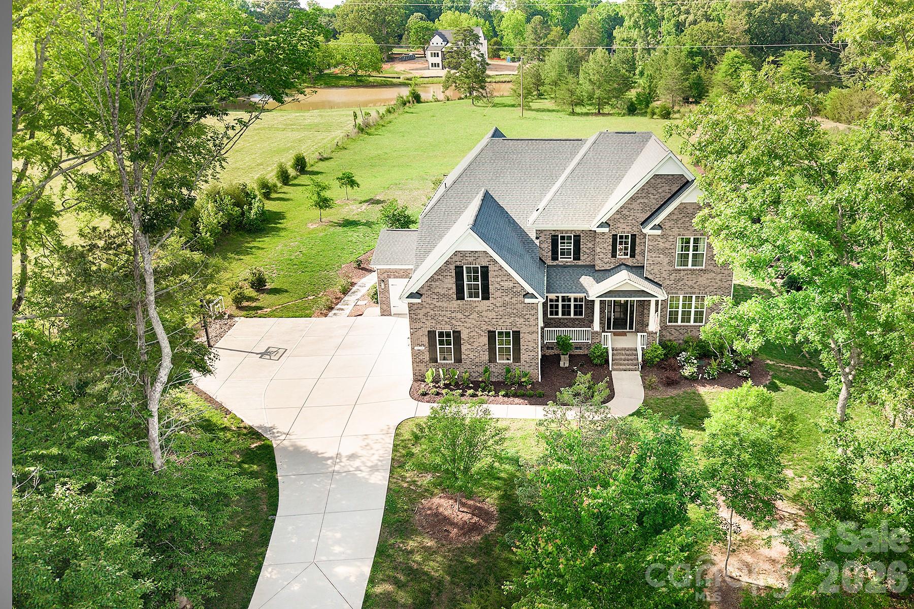 Experience luxury living and exceptional privacy in this stunning, like-new full brick home nestled on 2 full acres in sought-after Marvin. This impressive property offers an outdoor retreat featuring a large covered deck overlooking the expansive patio and backyard, custom landscaping, fire pit, outdoor kitchen with leathered granite countertops and gas grill, extended driveway, and thoughtfully added trees for enhanced privacy. The desirable floor plan features 5 spacious bedrooms, each with its own ensuite bath, including a main-level guest suite. The chef’s kitchen showcases an oversized island, quartz countertops, herringbone tile backsplash, gas range, and a highly functional walk-in pantry with beverage fridge. Luxury details continue throughout with updated lighting and ceiling fans, custom built-ins in the library, fresh interior paint, and a beautifully upgraded fireplace with tile surround, floating mantle, and custom shelving. The under-stair space has been thoughtfully finished as a dedicated dog room or “doggy condo.” The luxurious primary suite offers a spa-like bath and expansive walk-in closet. Additional highlights include a 4-car garage with epoxy-coated floors and freshly painted interior, built-in irrigation, upgraded oversized gutters, large bonus room, and a cul-de-sac lot. Conveniently located minutes from top-rated Marvin schools. Schedule your private tour today!
