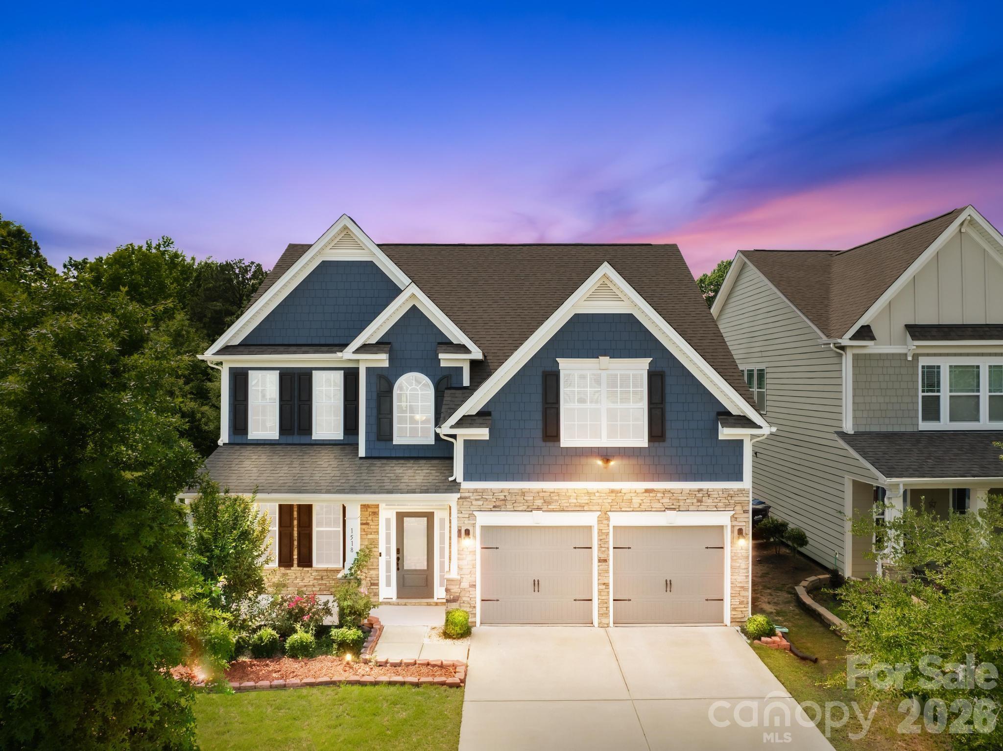 Tucked in one of Fort Mill's most sought-after neighborhoods, this stunning 5-bed, 3-bath home is just a short walk from the community pool and playground! Exceptional curb appeal with blue-gray shake siding, stacked stone accents, and a covered front porch welcomes you home. Inside, a dramatic two-story foyer with soaring ceilings, arched transom window, and rich hardwood floors makes a lasting first impression. Elegant picture-frame wainscoting and iron-and-wood stair balusters add a custom touch throughout.

The open-concept great room features a gas fireplace flowing into a gourmet kitchen with granite counters, gas cooktop, double wall ovens, custom range hood, subway tile backsplash, large island with seating, and a butler's pantry. The main floor also includes a guest bedroom with full bath — perfect for in-laws or a home office.

Upstairs, the primary suite offers a tray ceiling, garden soaking tub, frameless glass shower, dual granite vanity, and walk-in closet. Two additional bedrooms, a huge media/bonus/bed room pre-wired for a projector, full hall bath, and upstairs laundry complete the second floor. The private, fully fenced backyard backs to a wooded buffer with no rear neighbors and features a recently installed oversized concrete patio — ideal for entertaining. The home is wired throughout with structured CAT6 ethernet cabling for hardwired internet connectivity and comes equipped with a Ring video doorbell and three Ring floodlight security cameras for whole-home peace of mind. Award-winning Fort Mill Schools and quick I-77 access!