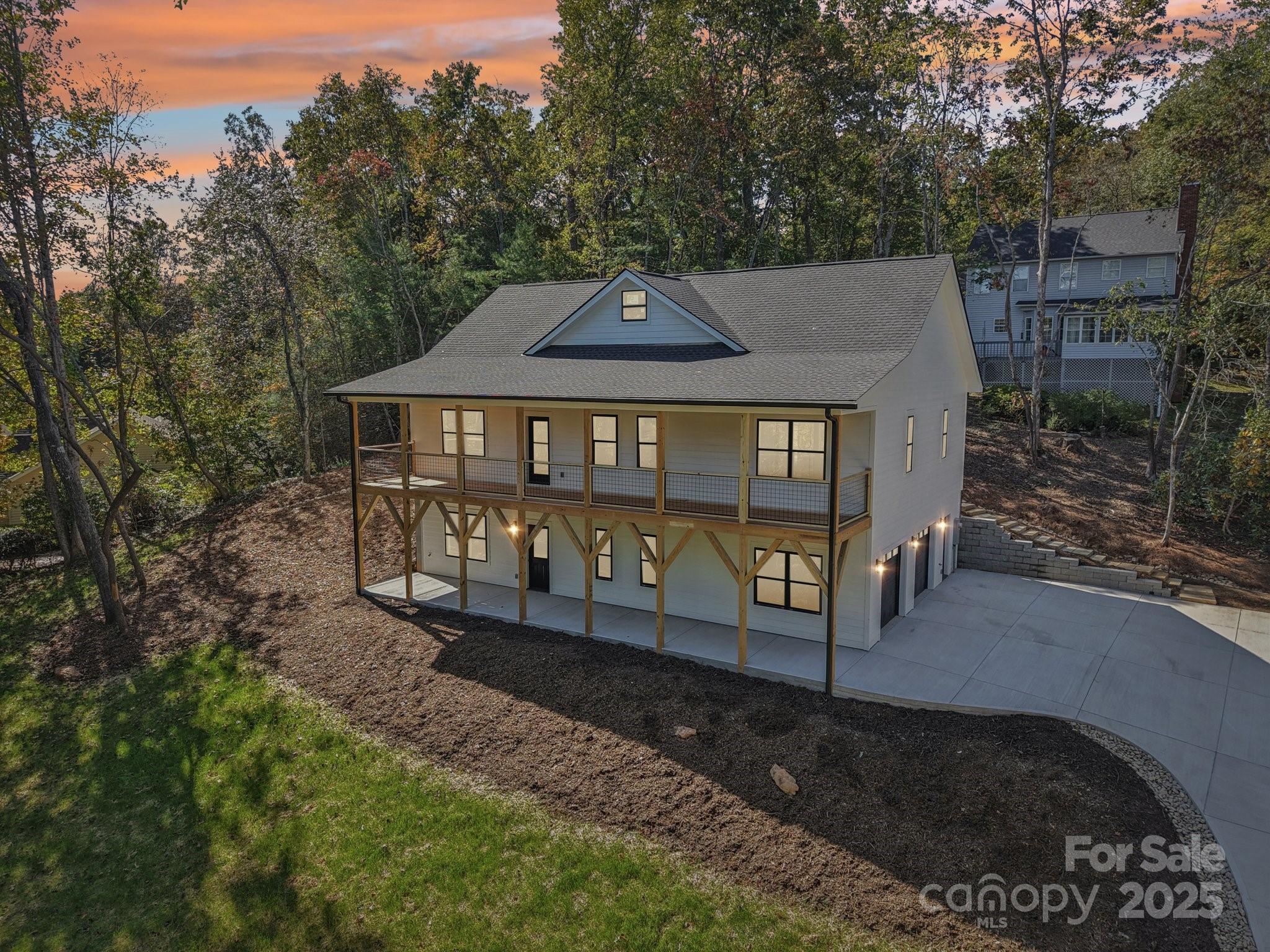 New Construction 3-bedroom, 3-bath home offers modern living in the highly desirable Mills Pointe neighborhood. Designed with exceptional attention to detail, this home showcases a bright, open-concept split-bedroom layout with soaring ceilings, a sleek electric fireplace, and luxury vinyl plank flooring that flows seamlessly across both levels.  The primary suite includes a spacious walk-in closet, custom tile shower, and dual vanity for added comfort. A partially finished lower level expands the home’s versatility, complete with a full bath, generous flex space, and a two-car garage—ideal for a home gym, media room, or guest quarters. Outdoor living is equally inviting with a large covered front porch that spans the full length of the home, capturing beautiful winter mountain views, and a rear deck off the dining area perfect for effortless entertaining. A spacious patio below further enhances the home’s connection to the outdoors. Centrally located between Asheville, Hendersonville and Brevard, and less than a few miles to the Asheville Airport.