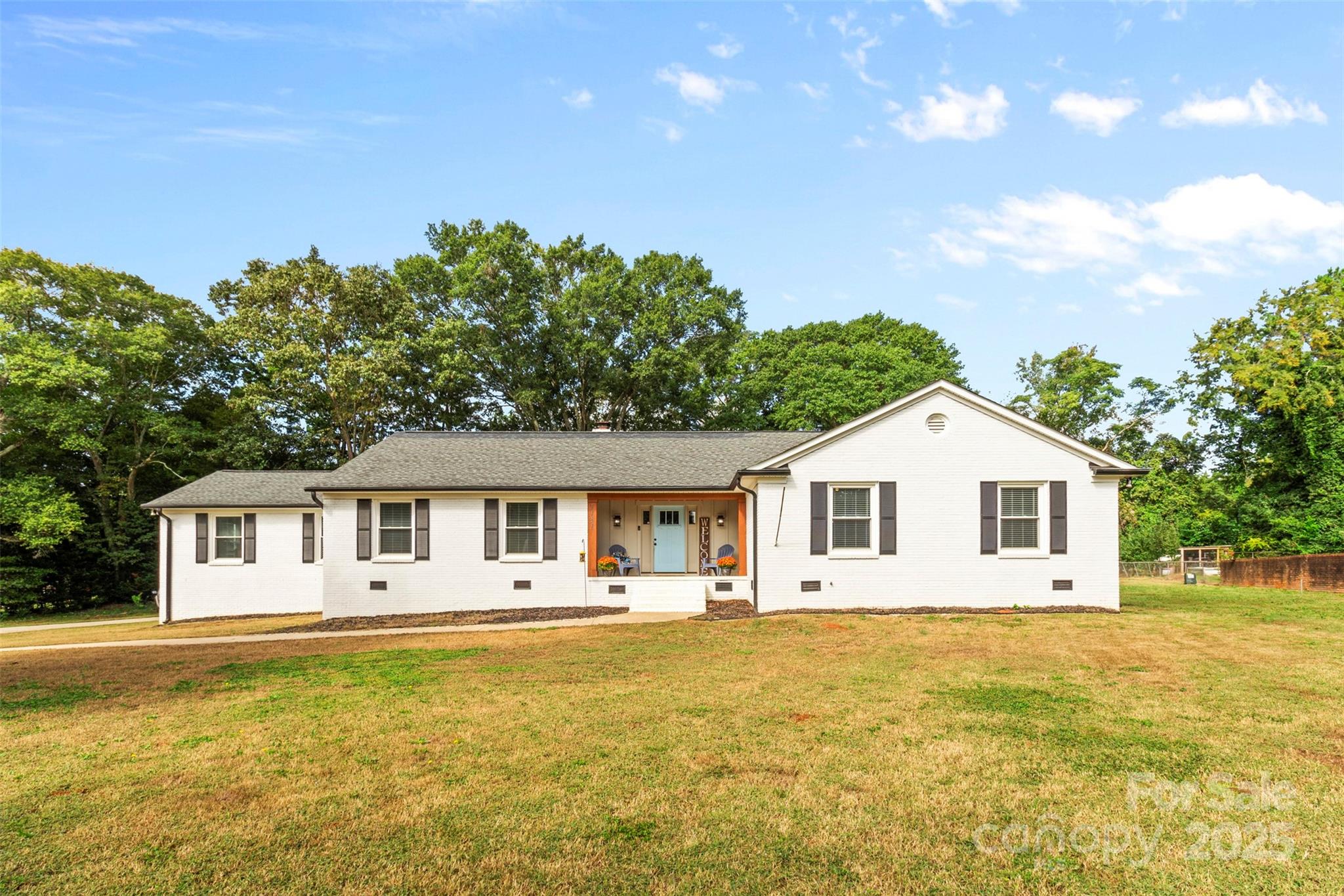 This stunning all-brick farmhouse-style ranch sits on 1.14 acres in the heart of Fort Mill. Recently renovated to blend modern conveniences with timeless charm, this home offers an open floor plan featuring rich hardwood floors & rustic wooden beams. The spacious living room, centered around a beautiful brick fireplace, flows seamlessly into the dining area, kitchen & sitting room—ideal for entertaining. The chef's kitchen boasts stainless steel appliances, a large island with quartz countertops & a striking backsplash. The primary suite offers a shiplap accent wall, tray ceilings, spacious walk-in closet w/ built-ins & a luxurious spa-like bathroom with a freestanding soaking tub & large walk-in shower. The secondary bedrooms are generously sized, filled with natural light & share two additional full baths. Outside, you'll enjoy a large covered porch, along with an uncovered patio area, providing plenty of space for outdoor living. New roof, vapor barrier & refinished hardwoods 12/24.