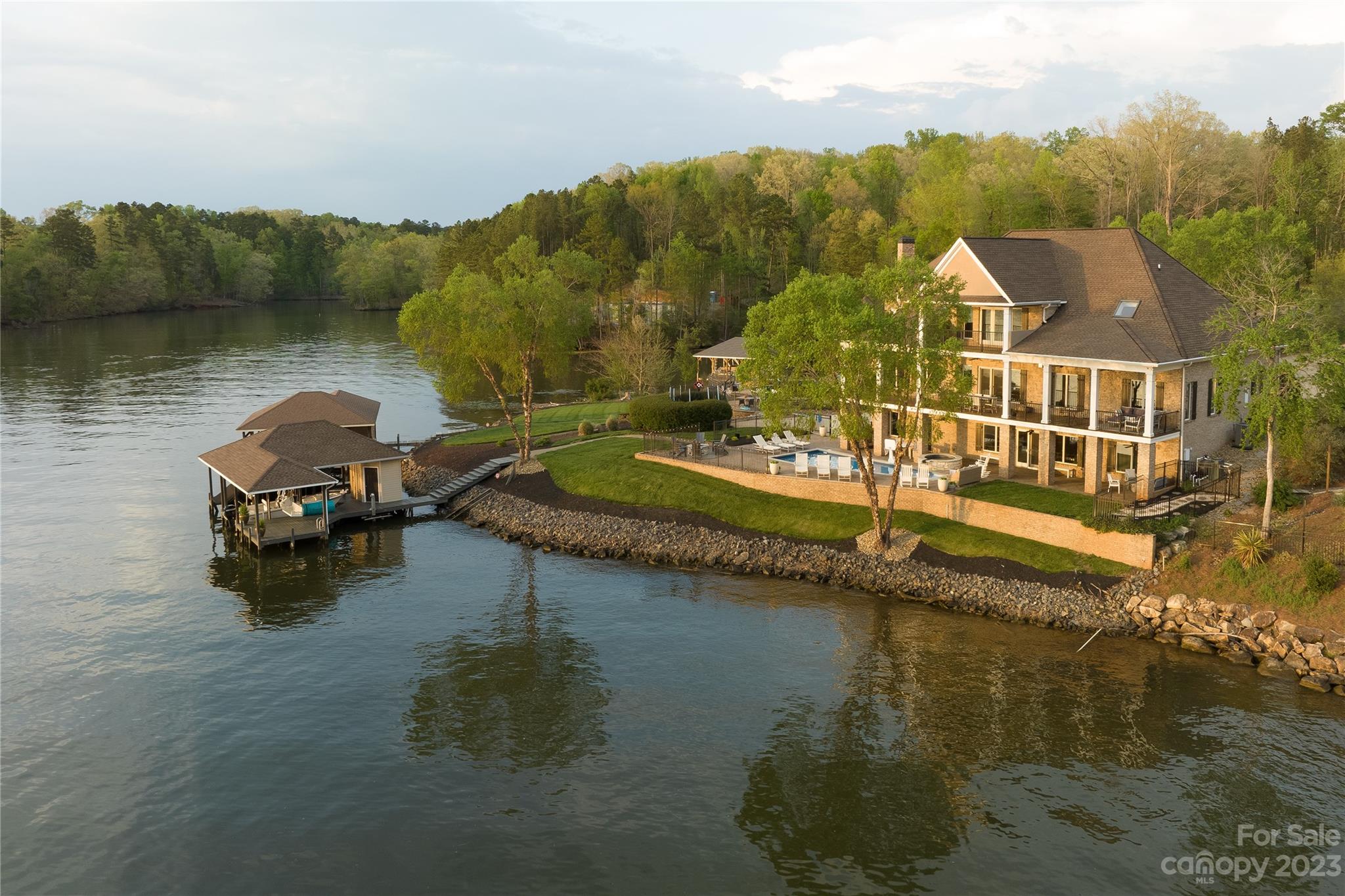 Stately Lake Tillery home on an ultimate main channel point lot located in an upscale desirable gated community. The huge breezy covered porch stretches the entire length of the home and is the perfect place to gather with loved ones. The spacious outdoor entertainment areas, inground heated pool, waterfall hot tub, and fire pit are rivaled only by the new professionally updated kitchen and interior.  For comfort and privacy there are 5 bedrooms and 5 1/2 baths, 4 of which are ensuite .  A dramatic circular staircase greets you at the lake view entrance and leads to a third floor loft and primary suite. The third floor also features a private covered balcony, spacious primary bath, huge walk in closets and ample walk in storage. The three story elevator is there should you choose. The large majority of the 5,871 heated living area is above grade adding height to the long range views. The three car garage has extra storage. Just a gentle sloped walk to the two bay covered boathouse.
