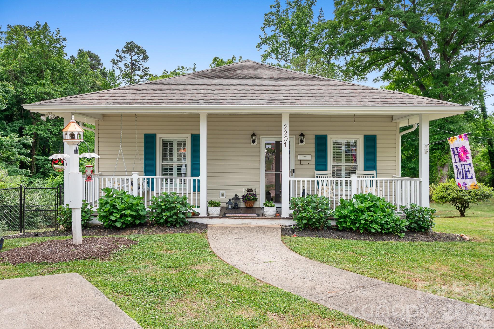 Absolutely adorable 1900 bungalow that stands out head and shoulders above most, you've got to see this charming Belmont mill home to believe it. Your buyers will be charmed too! The front porch extends the full length of the home front of the home, with plenty of "rocking chair" space to enjoy on lazy summer afternoons. The vinyl siding could free you up from exterior projects so you can actually enjoy the front porch!  Stepping inside, the first thing you’ll notice are the LVP flooring, fresh paint (2 years ago) and plantation shutters, giving this home a classic, pampered appearance.  The living room and bedrooms boast attractive lighted ceiling fans that help disperse the heat and cool air efficiently throughout the home so you’re always comfy.  The bedroom closets feature custom closet systems. Laundry room handles full-sized washer and dryer, and lets out onto the rear covered deck. The eat-in kitchen features Viatera quartz counter tops, a built-in microwave oven, stainless steel appliances and subway tile backsplash. New tub/shower by Bath-Fitters in 2018. Storm doors installed in 2019, LED gutters in 2020, LG stove /oven, dishwasher, dishwasher and microwave.  All fencing is chain-link, there are two separate outbuildings, one of which is cooled by a window A/C unit that conveys. Extra parking pad is covered by extra tall RV covering.  There is a tankless, on-demand hot water heater located in the stand-up crawl space. The location of this dream-home is exciting too, so you’ll appreciate the fast access to I-85. Come see this hidden Belmont gem but be prepared to end your home search once you see this one!!!