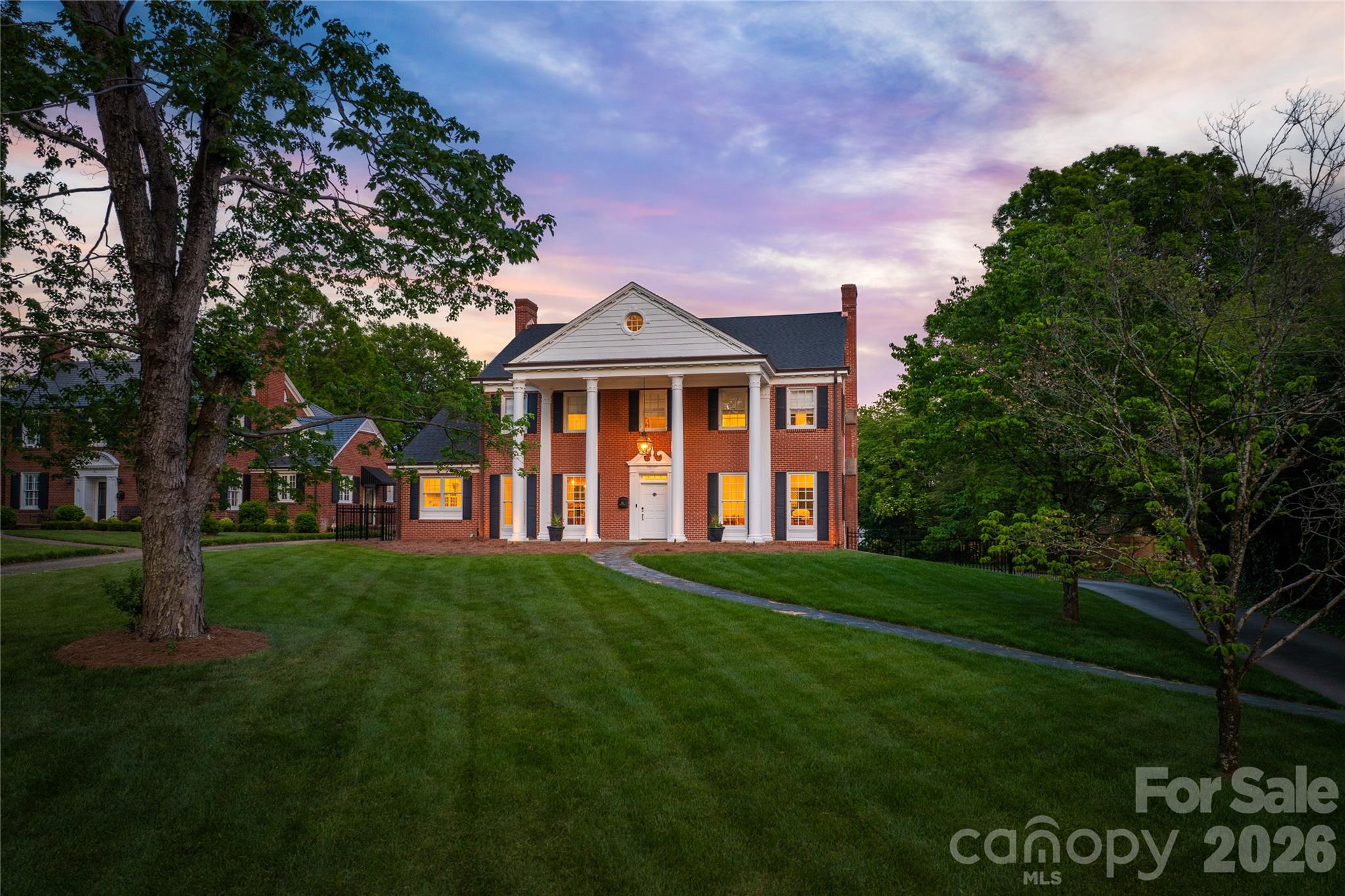 Set along one of Morganton’s most treasured streets, this timeless brick Colonial sits on a rare 1.36-acre flat lot with an expansive, fully fenced backyard, creating a private in-town retreat just three blocks from downtown Morganton’s boutique shopping, dining, and schools.

Originally built in 1940 and thoughtfully renovated by Ridgeline Building Corp., the residence honors its classic character while introducing refined finishes and elevated functionality designed for contemporary living. Sun-filled interiors showcase beautiful millwork, hardwood floors, curated finishes, and gracious gathering spaces.

The main level is designed for both elegant entertaining and comfortable everyday living, featuring a formal living room anchored by a fireplace, a formal dining room with original corner built-ins, a richly appointed study with wet bar, and a warm, inviting den lined with custom built-ins and its own wet bar. A gourmet kitchen with breakfast nook and a stylish half bath complete the main level. The kitchen is exceptionally appointed with custom cabinetry and a suite of premium integrated appliances, including a Wolf 48-inch six-burner range, warming drawer, Sub-Zero refrigerator, refrigerator drawers, dual dishwashers, and a built-in Miele coffee system.

Upstairs, four spacious bedrooms includes two en suite retreats and two additional bedrooms connected by a Jack-and-Jill bath. The versatile attic level features a playroom plus a (fifth) bedroom or recreation space complete with wet bar. A laundry room and full bath complete this level. The basement-level studio-style guest space, complete with kitchenette and full bath, offers comfortable accommodations for visiting guests, or an au pair suite.

Practical luxuries include two laundry rooms, abundant storage, a security system, exercise/play space, a two-car garage with attached garden shed, and irrigation system.

With only three owners in its history, this impeccably renovated residence represents a rare opportunity to own one of Morganton’s landmark homes — where historic charm, modern craftsmanship, and an unparalleled setting come together for a once-in-a-generation opportunity.

Ideal location only 90 minutes from Charlotte, 45 minutes to Asheville and Blowing Rock.