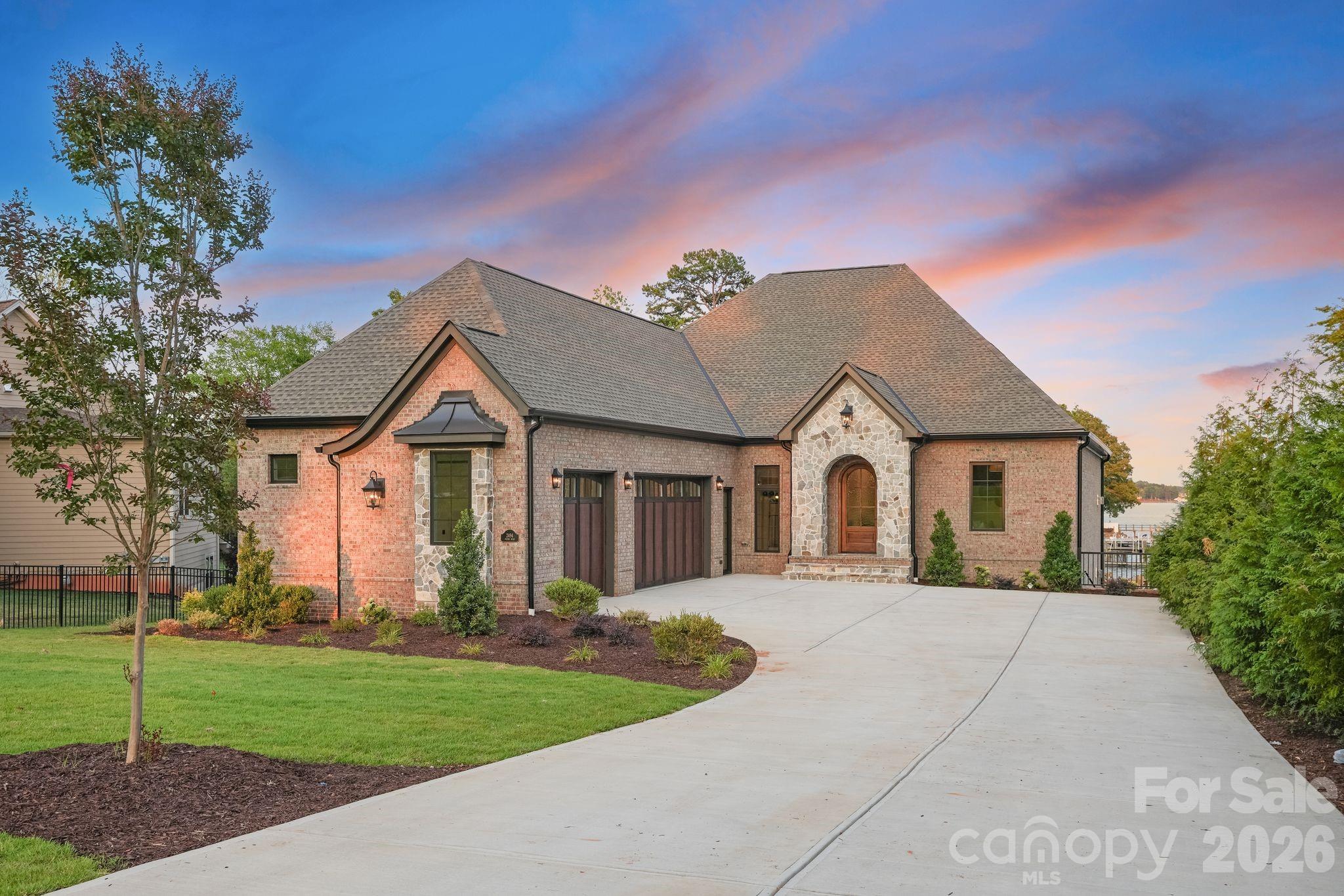 Experience the pinnacle of Lake Norman waterfront living in this new construction masterpiece by Planishek Properties.  Perfectly positioned on one of Lake Norman's most desirable stretches, this custom-built ranch with a fully finished walk-out basement offers an elevator servicing both levels, and wide-open main channel views that capture your attention from the moment you enter the home. Designed with effortless luxury and entertaining in mind, the soaring vaulted great room is framed by expansive windows that showcase water views while filling the home with natural light.  The open-concept layout seamlessly connects the living room, dining area, and chef-inspired kitchen, creating an inviting space for everyday living.  The kitchen is a showpiece, featuring honed quartz countertops, a spacious walk-in pantry, separate full-size refrigerator and freezer, premium JennAir appliances, a gas range, and an oversized island that naturally becomes the heart of the home.  Wake up every morning to panoramic sun-rise lake views from the primary suite, complete with vaulted ceilings, wall of windows, a spa-inspired bathroom featuring a soaking tub, oversized walk-in shower, dual vanities, and generous his-and-hers walk-in closets.  The main level also includes a private ensuite bedroom, an additional guest bedroom, a full bath, dedicated office, and spacious laundry room with drop zone.  The walk-out lower level is designed for exceptional entertaining and recreation. Enjoy a recreation family room anchored by a beautiful fireplace, a dedicated media room, fitness room, and an impressive bar and kitchenette featuring a dishwasher, sink, ice maker, beverage refrigerator, and an incredible walk-up serving window highlighted by a custom stone accent wall that perfectly complements the fireplace, plus tons of storage. Two additional bedrooms and another full bathroom provide ample space for family and guests.  Outside relax on the travertine terrace overlooking the sparkling heated pool and spa while taking in main channel views.  Spend evenings gathered around the fire pit and enjoy the fully fenced backyard. Your private dock is complete with boat slip, making it effortless to enjoy everything Lake Norman has to offer.