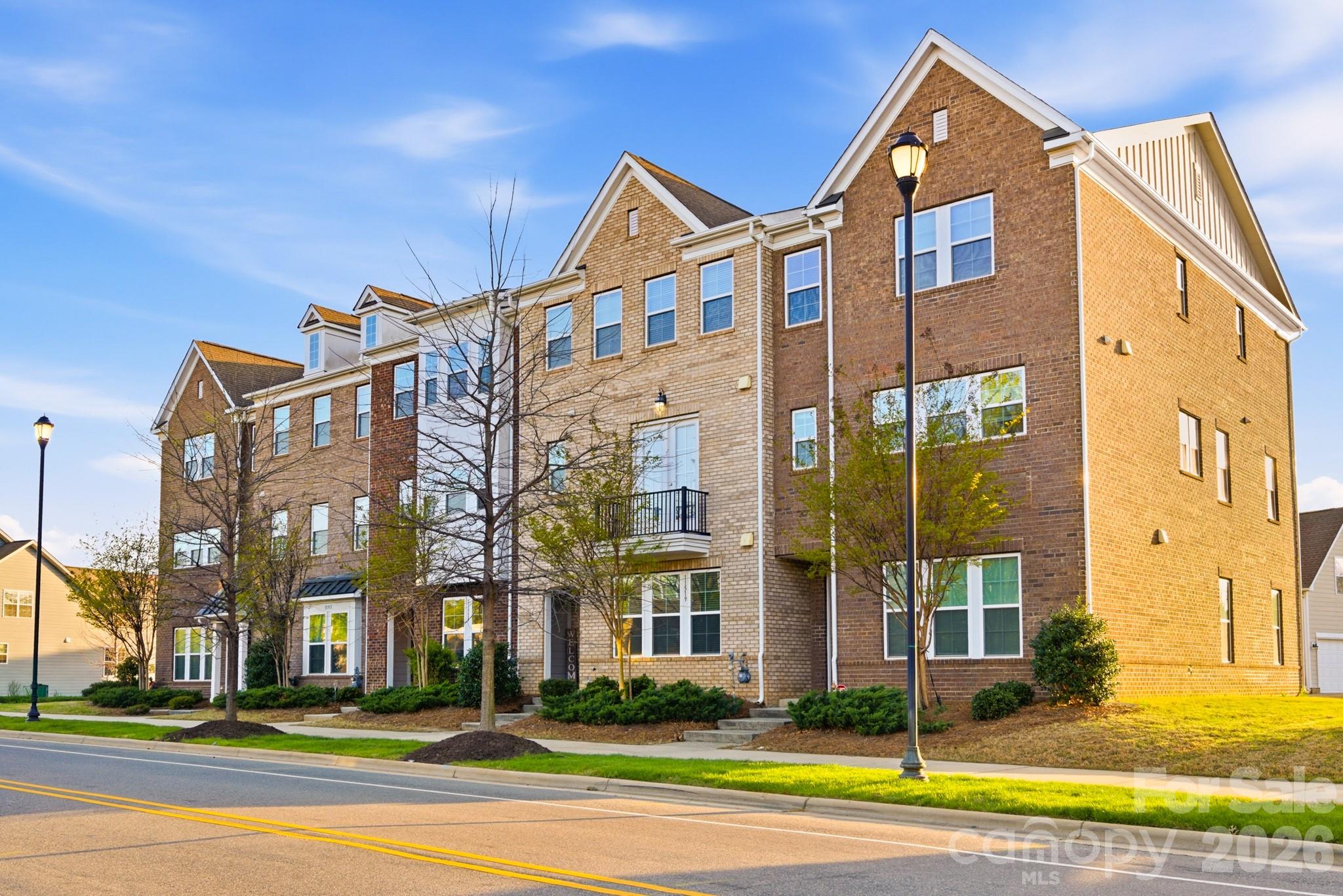 Welcome to one of Charlotte's most sought-after addresses, where the convenience of city living meets the warmth of a true neighborhood. Built in 2019, this stunning three-story brick townhome puts you steps from everything that makes Rea Farms and Waverly two of South Charlotte's most exciting communities — world-class dining, boutique shopping, green space, and more, all without ever getting in your car. From the moment you step inside, the quality and thoughtfulness of this home are impossible to miss. Rich hardwood flooring flows throughout the main living level, catching the natural light that pours in through oversized windows and the glass-paneled balcony door. The open-concept layout connects the living and dining areas to the kitchen in a way that makes entertaining feel effortless, anchored by a gorgeous staircase with stained wood handrails and decorative wrought iron balusters. The living room features a built-in media niche with floating shelves and opens directly to the private balcony with wood-plank decking and black iron railing. The chef's kitchen is a true showstopper, finished with crisp white shaker cabinets, thick granite countertops, and a large center island illuminated by elegant pendant lights. A full stainless steel appliance suite includes a gas range, built-in microwave, and counter-depth refrigerator, while the subway tile backsplash and recessed lighting add that extra layer of refinement. The top floor is home to a spacious primary bedroom with crown molding and a private en-suite bath that rivals any luxury hotel, featuring a raised double vanity topped with granite, a frameless glass-enclosed tile shower with a built-in bench and decorative mosaic accent, and a separate private water closet. Three additional bedrooms offer hardwood floors, ceiling fans, and great natural light — one even features a charming built-in wall desk and shelving, ideal as a home office or study. Three of the four bedrooms include walk-in closets, and two full secondary bathrooms each feature raised vanities with granite countertops and tub/shower combinations. A powder room on the main level and a dedicated laundry room with a full-size front-load washer and dryer round out the thoughtful layout. The home is also fully loaded with smart technology, including a Honeywell smart thermostat system, Kwikset smart front door lock, Ring video doorbell, and three Ruckus wireless access points that deliver commercial-grade Wi-Fi to every corner of the home. Storage is everywhere you need it — three walk-in closets, a finished area beneath the staircase, two discreet storage rooms flanking the balcony, and an oversized rear-entry two-car garage. And then there's the location: Waverly's walkable streetscape is the kind of place you'll find yourself wandering on a Saturday morning, grabbing a cup from Breezeway Coffee Roasters before browsing the boutiques, then settling in for dinner at The Porter's House or Via Roma. Whole Foods anchors the grocery run, and on any given night you have your pick of casual spots like Carolina Ale House or something more elevated at Foxcroft Food & Wine. A Lifetime Fitness, Hand & Stone Massage, and a full lineup of wellness options make it easy to take care of yourself without ever getting on the highway. Just steps away, Rea Farms adds even more — Little Mama's Italian and The Improper Pig have become neighborhood staples, and Harris Teeter handles the everyday errand list. Luxury finishes, smart technology, and a location that truly has it all — 11515 Red Rust Lane isn't just a place to live, it's a place to love coming home to.