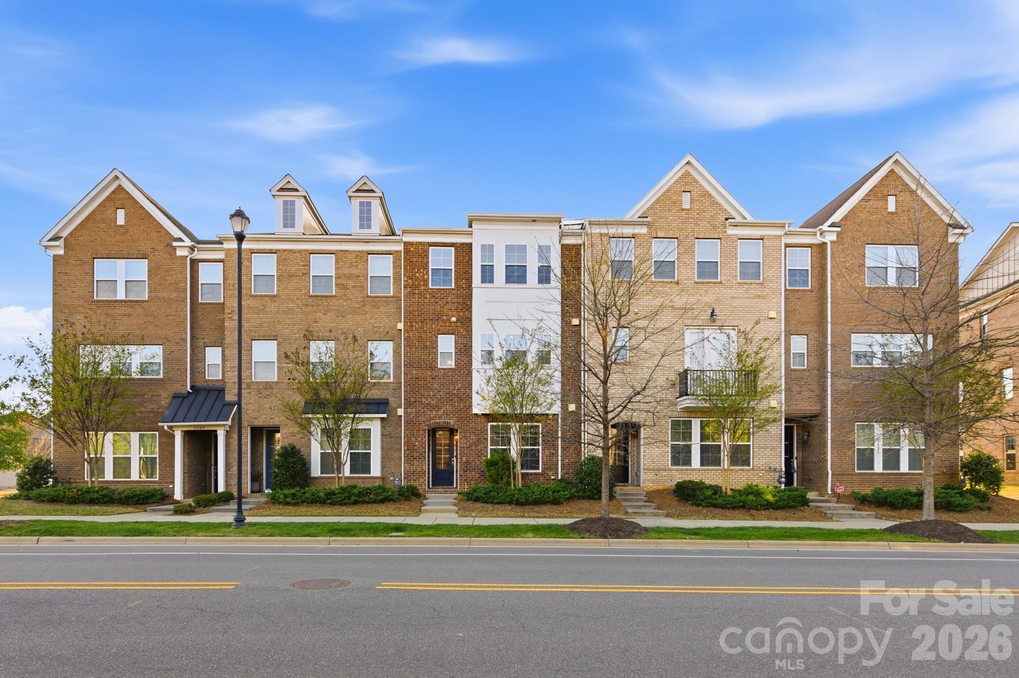 Welcome to one of Charlotte's most sought-after addresses, where the convenience of city living meets the warmth of a true neighborhood. Built in 2019, this stunning three-story brick townhome puts you steps from everything that makes Rea Farms and Waverly two of South Charlotte's most exciting communities — world-class dining, boutique shopping, green space, and more, all without ever getting in your car. From the moment you step inside, the quality and thoughtfulness of this home are impossible to miss. Rich hardwood flooring flows throughout the main living level, catching the natural light that pours in through oversized windows and the glass-paneled balcony door. The open-concept layout connects the living and dining areas to the kitchen in a way that makes entertaining feel effortless, anchored by a gorgeous staircase with stained wood handrails and decorative wrought iron balusters. The living room features a built-in media niche with floating shelves and opens directly to the private balcony with wood-plank decking and black iron railing. The chef's kitchen is a true showstopper, finished with crisp white shaker cabinets, thick granite countertops, and a large center island illuminated by elegant pendant lights. A full stainless steel appliance suite includes a gas range, built-in microwave, and counter-depth refrigerator, while the subway tile backsplash and recessed lighting add that extra layer of refinement. The top floor is home to a spacious primary bedroom with crown molding and a private en-suite bath that rivals any luxury hotel, featuring a raised double vanity topped with granite, a frameless glass-enclosed tile shower with a built-in bench and decorative mosaic accent, and a separate private water closet. Three additional bedrooms offer hardwood floors, ceiling fans, and great natural light — one even features a charming built-in wall desk and shelving, ideal as a home office or study. Three of the four bedrooms include walk-in closets, and two full secondary bathrooms each feature raised vanities with granite countertops and tub/shower combinations. A powder room on the main level and a dedicated laundry room with a full-size front-load washer and dryer round out the thoughtful layout. The home is also fully loaded with smart technology, including a Honeywell smart thermostat system, Kwikset smart front door lock, Ring video doorbell, and three Ruckus wireless access points that deliver commercial-grade Wi-Fi to every corner of the home. Storage is everywhere you need it — three walk-in closets, a finished area beneath the staircase, two discreet storage rooms flanking the balcony, and an oversized rear-entry two-car garage. And then there's the location: Waverly's walkable streetscape is the kind of place you'll find yourself wandering on a Saturday morning, grabbing a cup from Breezeway Coffee Roasters before browsing the boutiques, then settling in for dinner at The Porter's House or Via Roma. Whole Foods anchors the grocery run, and on any given night you have your pick of casual spots like Carolina Ale House or something more elevated at Foxcroft Food & Wine. A Lifetime Fitness, Hand & Stone Massage, and a full lineup of wellness options make it easy to take care of yourself without ever getting on the highway. Just steps away, Rea Farms adds even more — Little Mama's Italian and The Improper Pig have become neighborhood staples, and Harris Teeter handles the everyday errand list. Luxury finishes, smart technology, and a location that truly has it all — 11515 Red Rust Lane isn't just a place to live, it's a place to love coming home to.