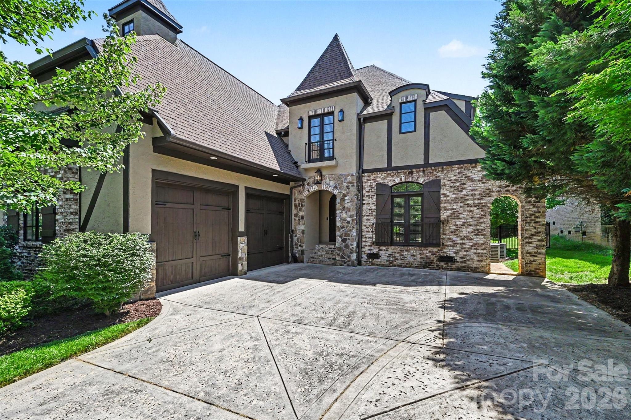 Located in the Olde Providence area, this elegant Tudor in the Chambery neighborhood is loaded with features and amenities and ready for its next owner! Starting on the exterior, find a level corner lot, lush landscaping, and an exterior that boasts stone, hard stucco, and brick finishes. Rear yard offers a private retreat and is highlighted by a covered rear porch with tongue and groove ceiling and then an extended travertine tile paver patio. Full roof replacement in 2024 and has transferable warranty. Step inside through the wrought iron and glass front door and find wide-plank pine hardwoods, fresh paint throughout (including trim), a soaring formal dining room, home office w/ french doors, powder room with artsy tilework, 2-story living room with coffered ceiling and gas fireplace, laundry area with plenty of cabinets/shelving and a cute pet spa, and a DREAM kitchen - pendant lights, island, tile backsplash, 2-tone cabinets (including 42" uppers with crown molding), stainless steel appliances including gas range and Sub-Zero refrigerator, and a fireplace in the kitchen! All throughout the house, find large custom windows, high ceilings, arched doorways, and more finishes to give it that contemporary-European feel! Main floor master suite with private fireplace, decorative ceiling beams, and an ensuite bathroom - dual vanities, walk-in tiled shower with bench, soaking tub, and oversized walk-in closet with custom shelving and pocket doors! Upper level features a giant bonus room with water connection for a wet bar, 3 guest bedrooms (2 connected with a jack and jill bathroom w/ walk-in shower and separate tub), and a guest bathroom with tub/shower insert. Prime location - close to SouthPark, golf, greenways, dining options, Uptown, and more!
