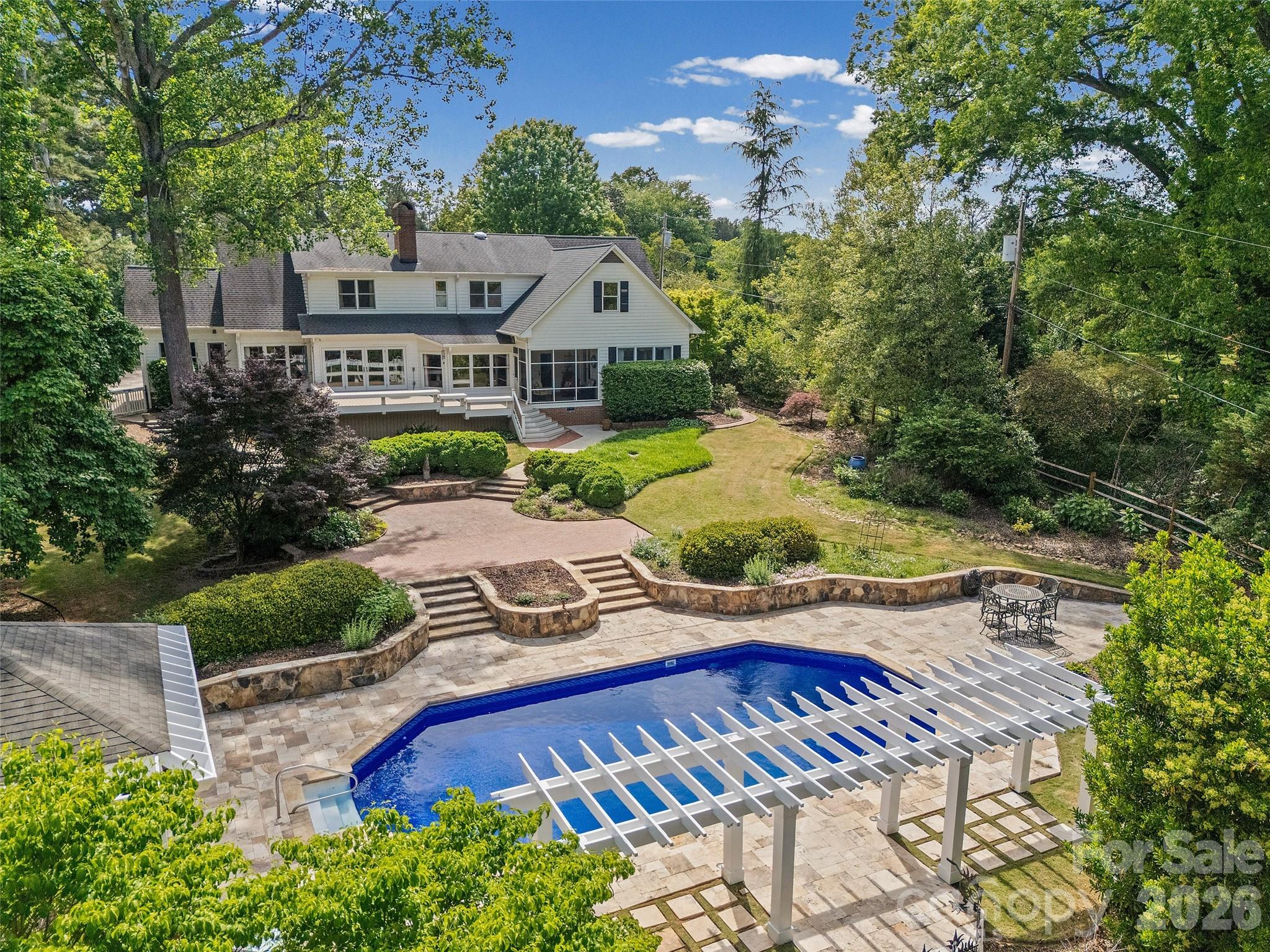 Nestled in the highly desirable and established Fairlawn neighborhood, this stately luxury residence offers timeless elegance, exceptional craftsmanship, and resort-style outdoor living. With 5 bedrooms and 4.5 bathrooms, this thoughtfully designed home blends refined sophistication with comfortable everyday living.
The spacious primary suite on the main level serves as a true retreat, featuring a spa-inspired bathroom, abundant closet storage, and private access to the screened porch, the perfect place to enjoy peaceful mornings overlooking the backyard oasis. A guest suite on the main floor provides ideal accommodations for visitors or multi-generational living. Upstairs, you’ll find three generously sized bedrooms, two full bathrooms, a welcoming loft/sitting area, and an expansive bonus room currently designed as a billiards space, offering endless flexibility for entertaining, recreation, or media use. Designed for both luxury and relaxation, the outdoor living spaces are simply stunning. A large deck overlooks the beautifully landscaped, private backyard where a gorgeous saltwater pool is surrounded by elegant travertine tile, creating a true resort-style experience at home. Throughout the home, impeccable quality updates shine, including a beautifully renovated kitchen, custom built-in cabinetry, and a striking custom front door that makes an unforgettable first impression. Every detail reflects exceptional care, craftsmanship, and timeless style in one of Rock Hill’s most sought-after neighborhoods.  Come see the lifestyle this home offers!
