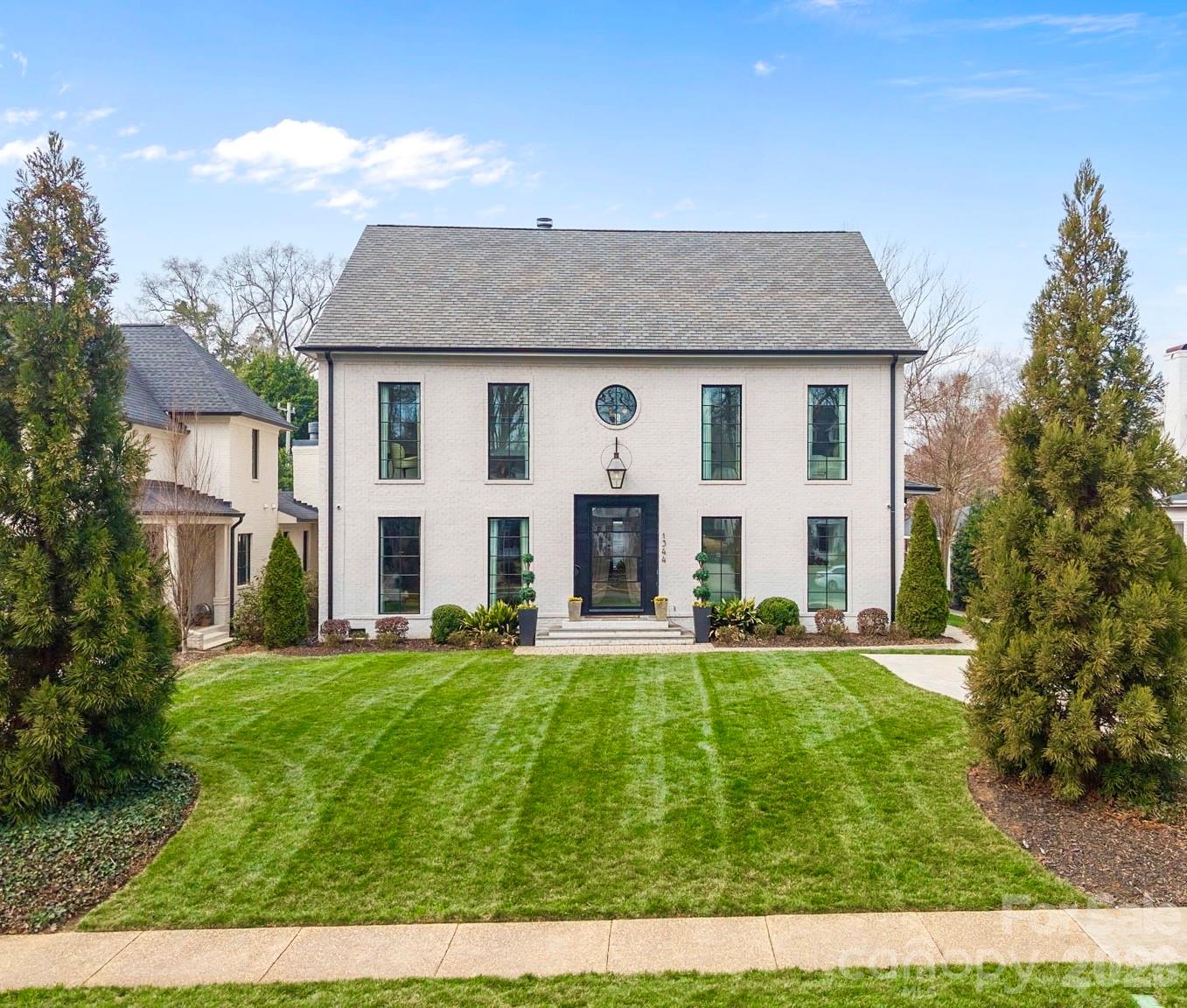 An EXQUISITE EASTOVER custom built residence blending timeless architecture with modern luxury. Curb appeal features tumbled brick, metal windows, bluestone accents, curated landscaping, and a dramatic steel-and-glass pivot entry door. Inside, light-filled interiors showcase white oak hardwood floors, custom trim, white-washed shiplap, exposed beams, and soaring ceilings. The Great Room boasts 15’ ceilings, transom windows, a custom fireplace with reclaimed white oak mantel, and a concealed Hall library with built-in shelving. Sliding glass walls in the Great and Dining Rooms open to a covered terrace with bluestone flooring, ceiling fan, and masonry fireplace, perfect for indoor-outdoor entertaining. The open chef’s kitchen features a gray-washed white oak waterfall island with Lavezzi leathered quartzite countertops, Silestone perimeter counters, marble backsplash, and custom cabinetry. Premium appliances include Sub-Zero refrigeration, integrated dual-zone wine tower, Wolf 48” dual-fuel range, and ASKO dishwasher, plus a dedicated beverage, prep and pantry area. The main-level primary suite offers vaulted ceilings, French doors to the landscaped yard, access to a private retreat, and a spa-inspired bath with freestanding tub, frameless glass shower, marble countertops, and walk-in closets. Upper levels provide four bedrooms with two ensuite, full laundry, den/media space, study/office, and a generous third-floor bonus room for exercise or a private study with a wall of closets for storage and walk-in attic storage. The upstairs left suite would function seamlessly as a secondary primary retreat. Additional highlights include two laundry rooms, energy-efficient construction, and a detached two-car garage. Convenient to shops and restaurants in the Myers Park and Eastover area with an easy commute to Uptown.